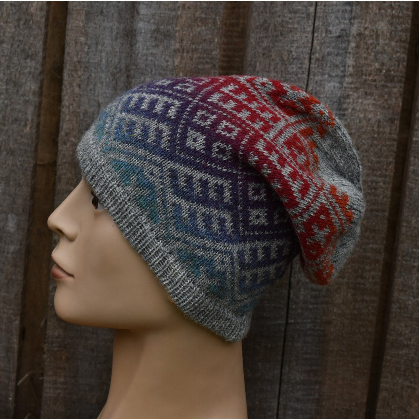 Knitted multicolored hat on a mannequin head against a textured brown background