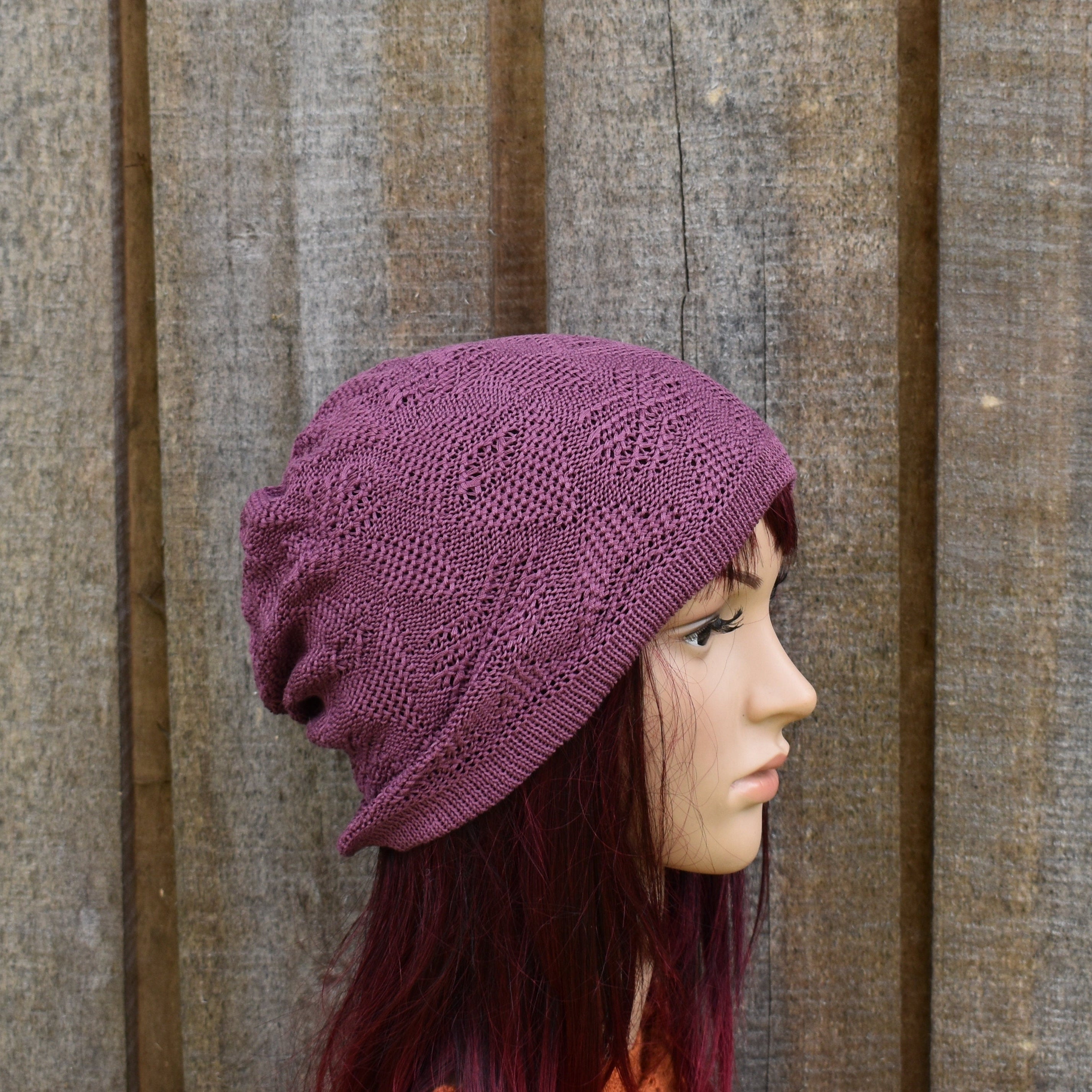 Woman wearing a purple knitted hat against a wooden background