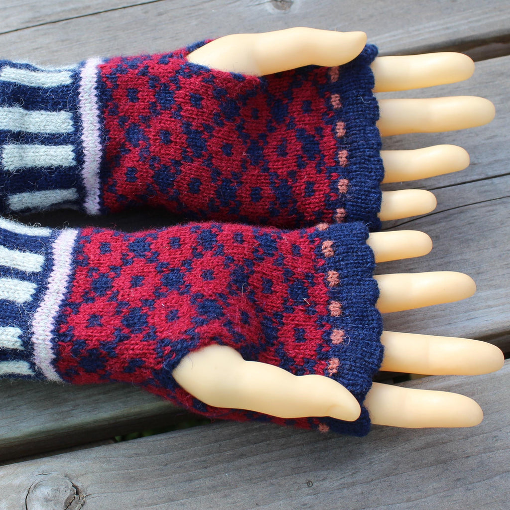 Pair of red and blue patterned fingerless gloves on a mannequin hand against a wooden background
