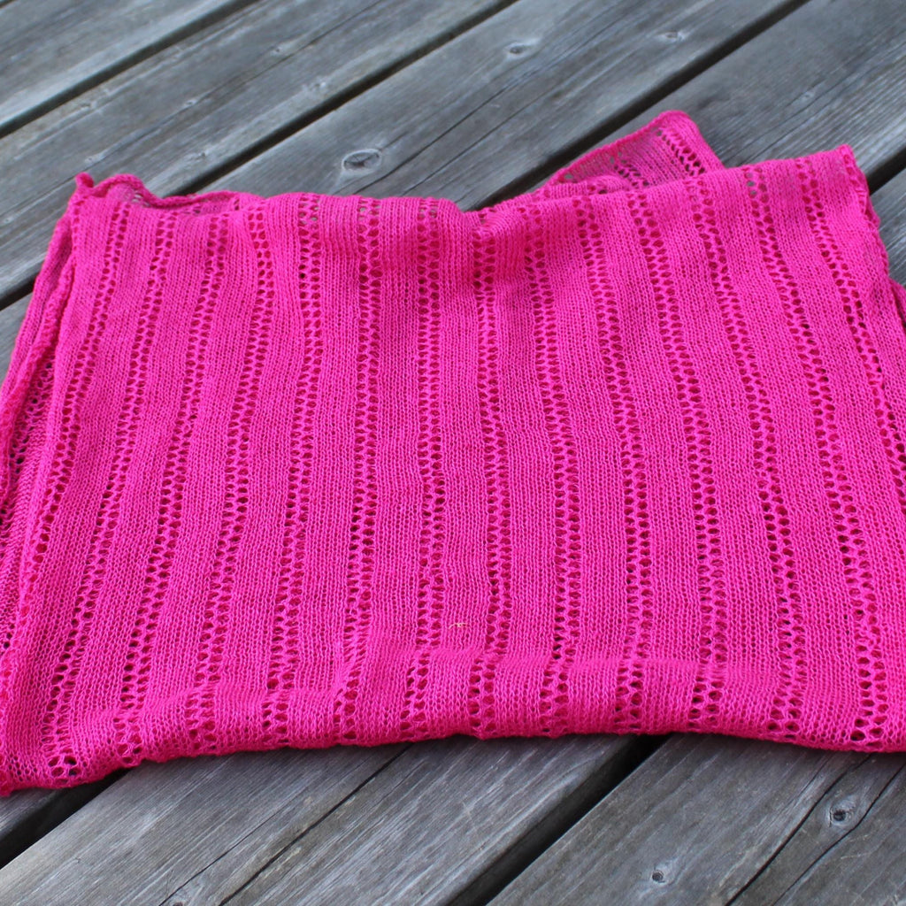 Pink knitted blanket on a wooden surface