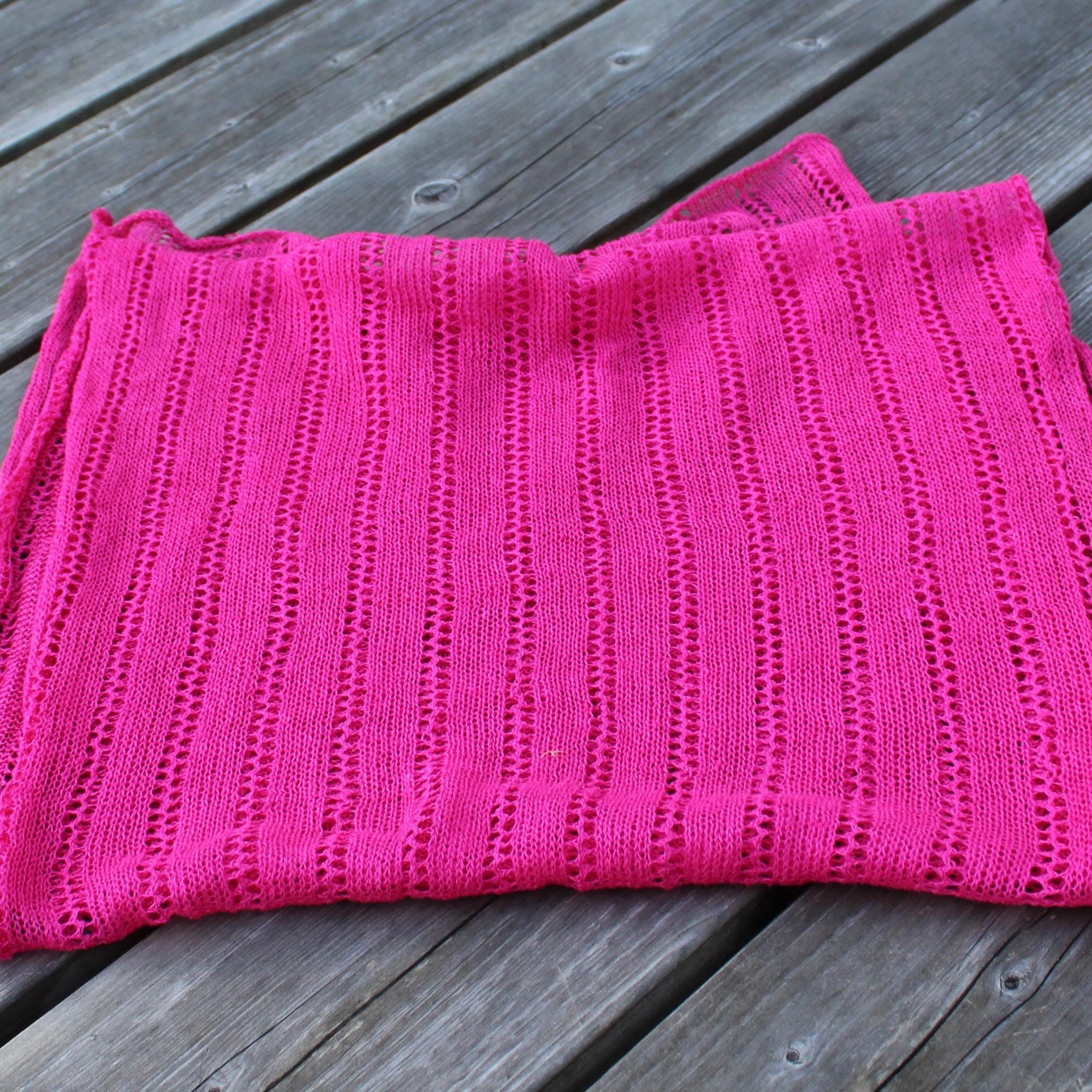 Pink knitted blanket on a wooden surface
