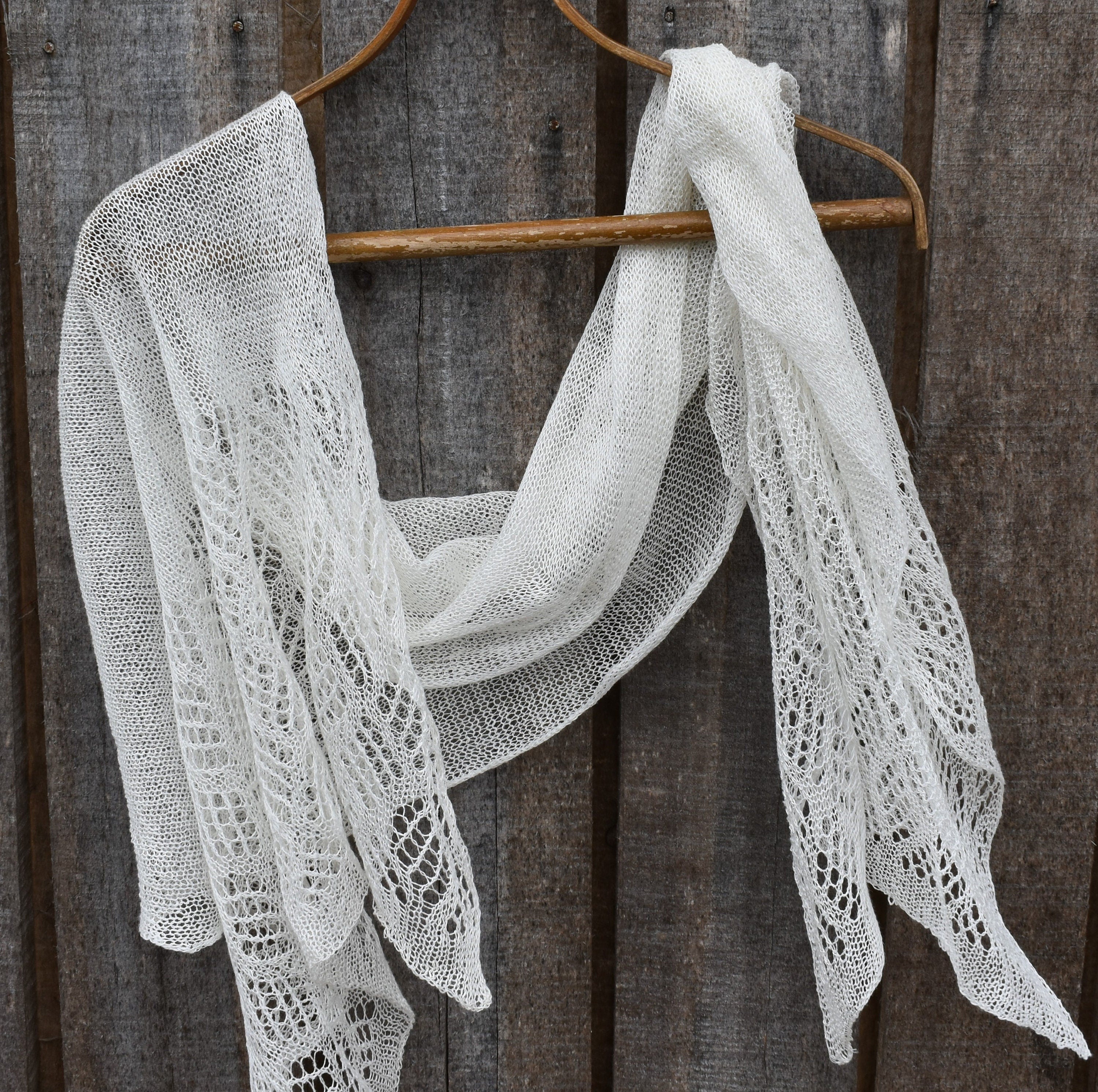 White lace shawl on a wooden hanger against a rustic wooden background
