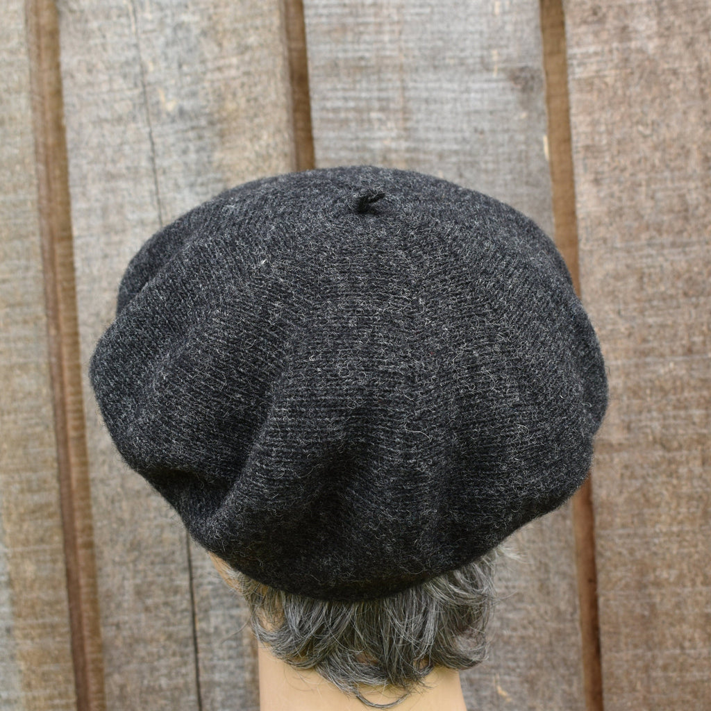 Dark gray knit cap on a mannequin head against a wooden panel background