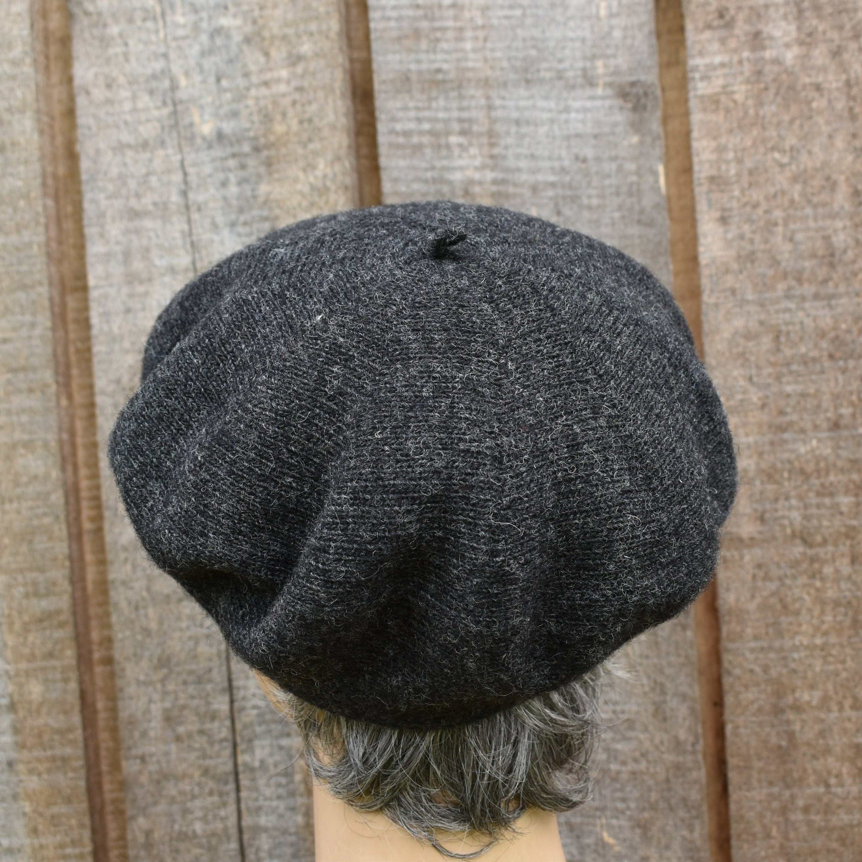 Dark gray knit cap on a mannequin head against a wooden panel background