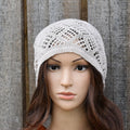 Mannequin head wearing a light gray knitted hat against a wooden background