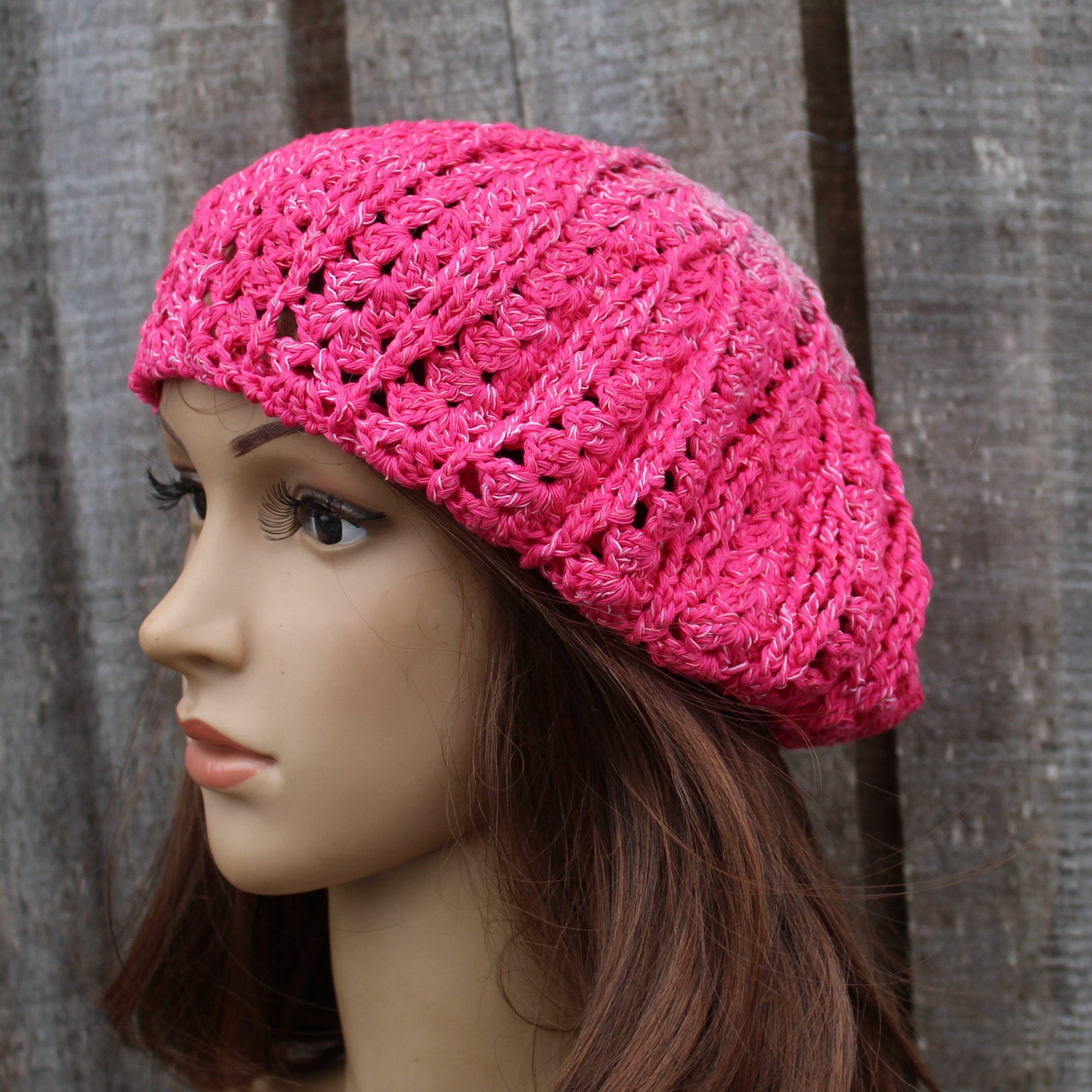 Mannequin head wearing a pink knitted hat against a wooden background