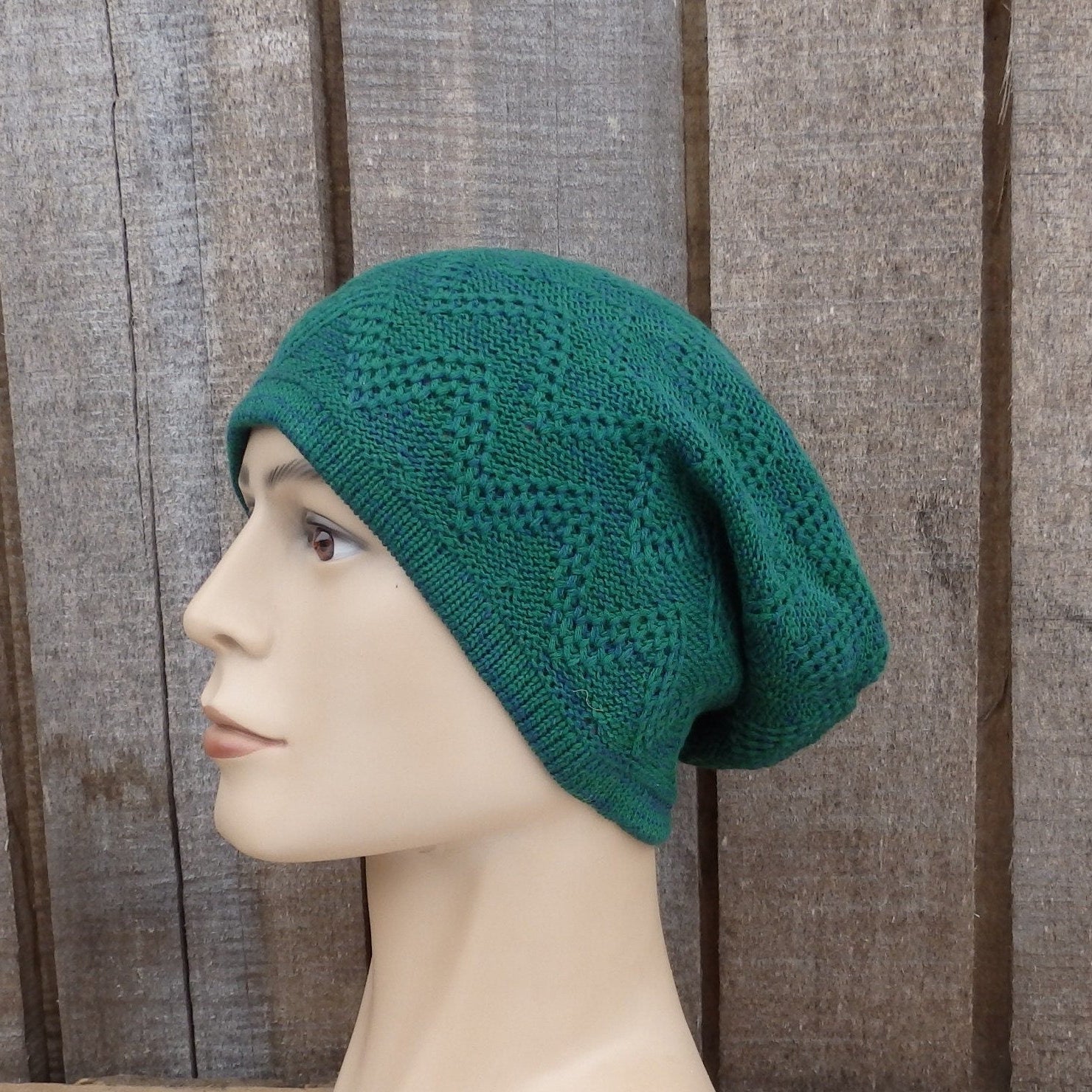 Green knitted beanie on a mannequin head against a wooden background