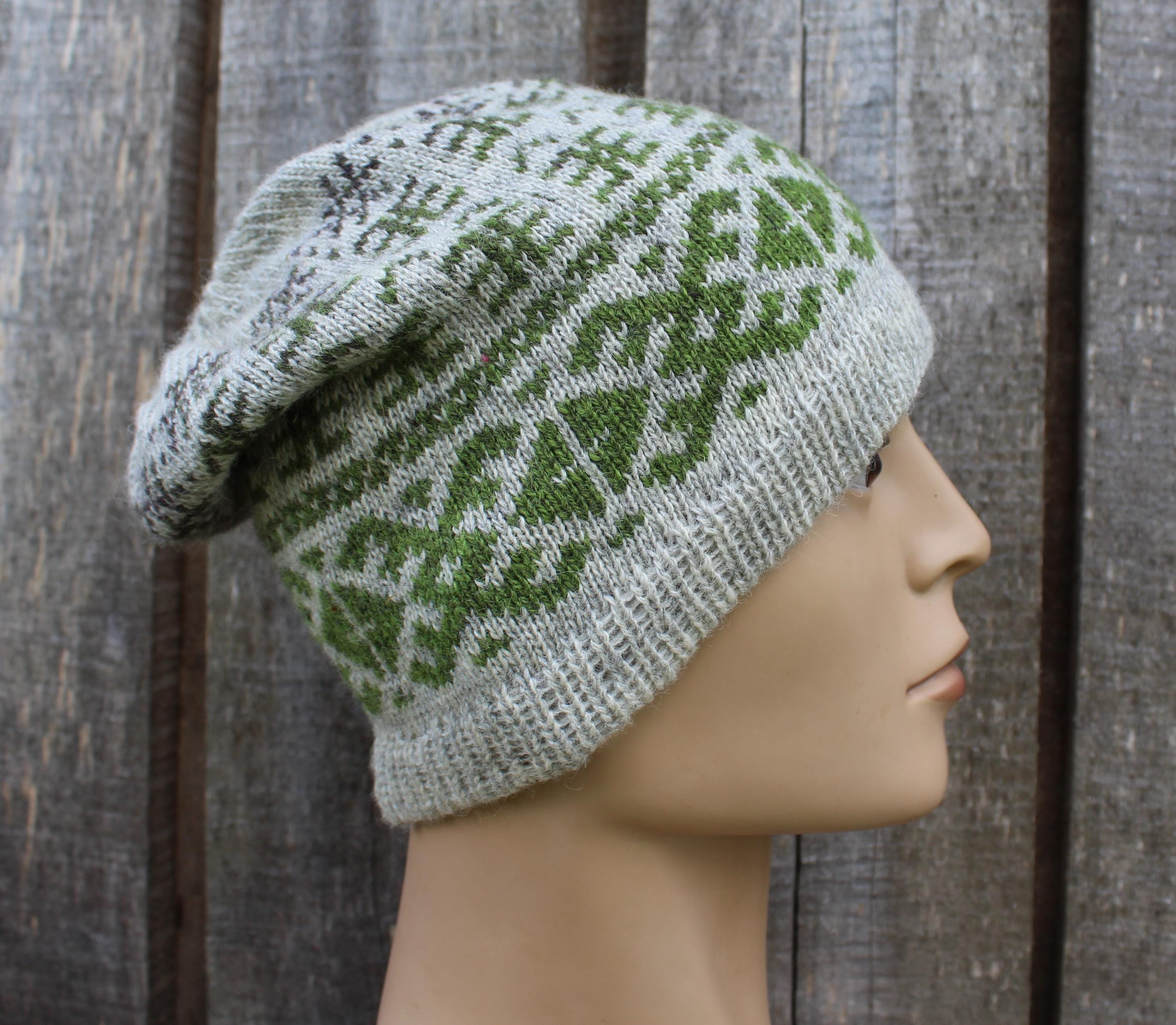 Knitted hat with green pattern on a mannequin head against a wooden background