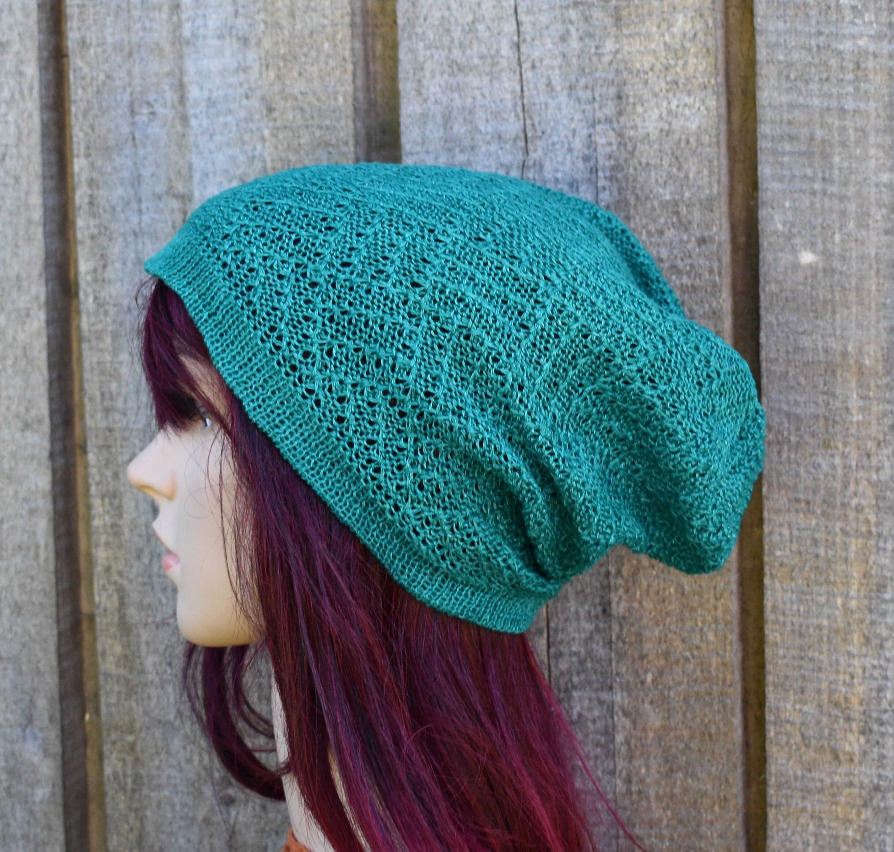 Green knitted hat on a mannequin head against a wooden background