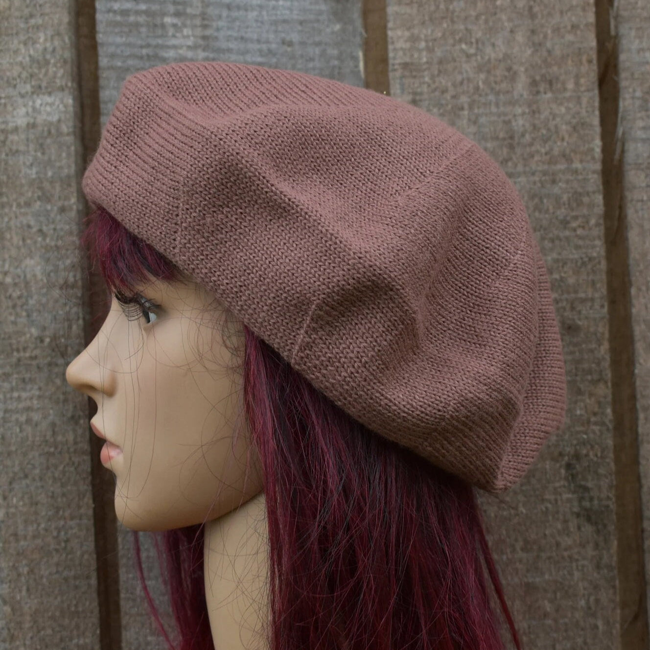 Brown knitted beret on a mannequin head against a textured brown background
