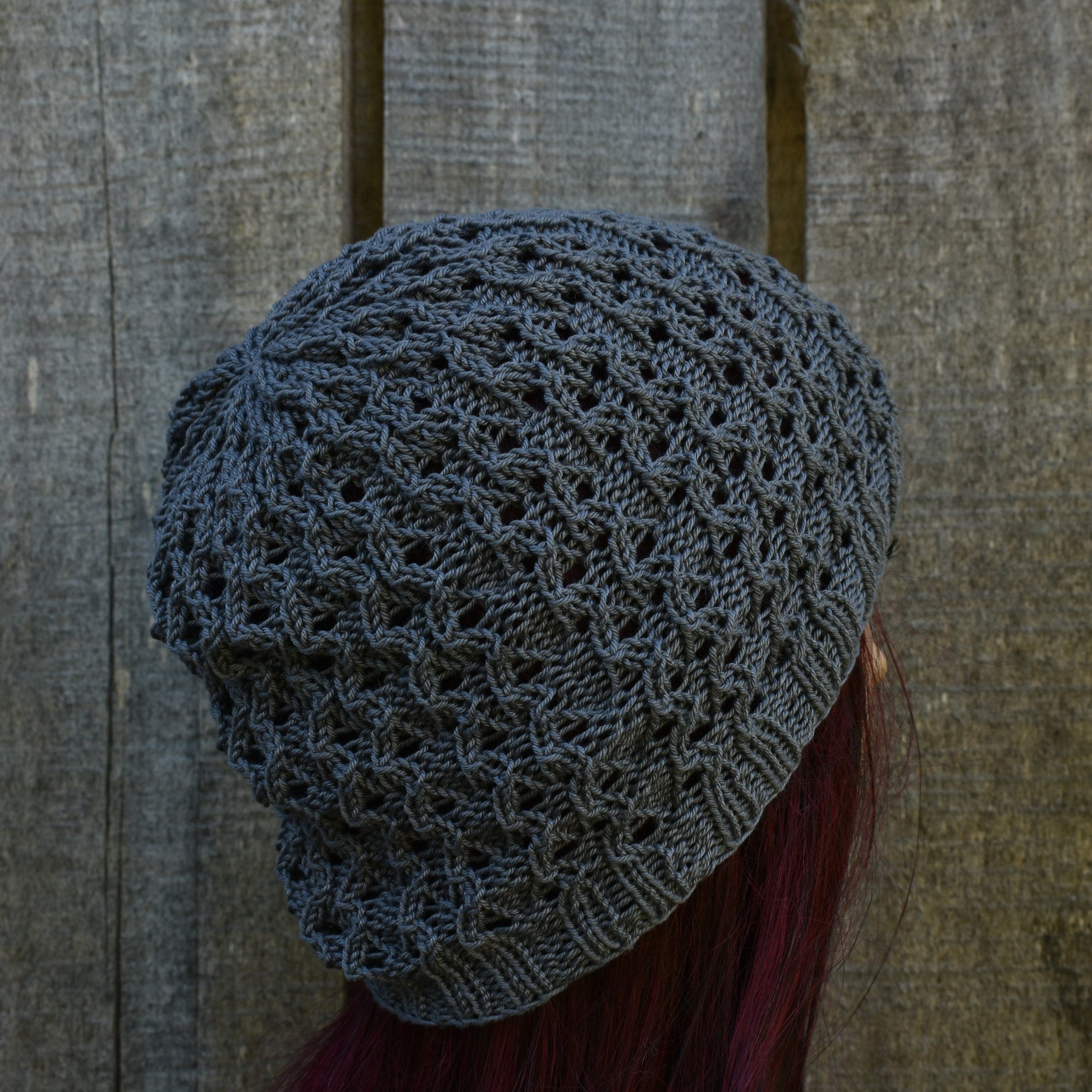 Gray knitted hat on a person with red hair against a wooden background