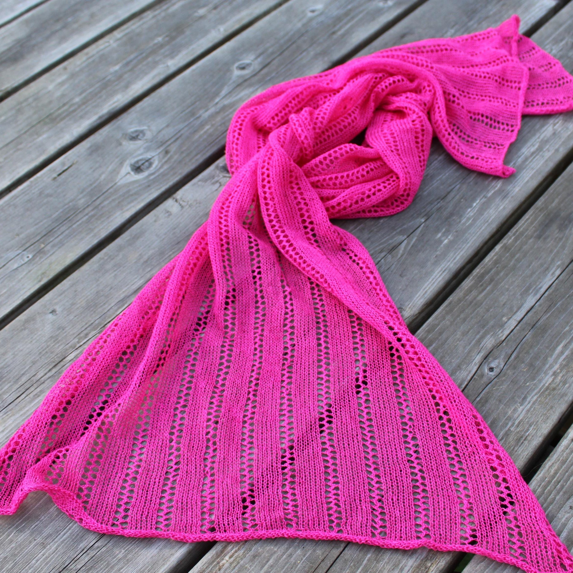 Pink knitted scarf on a wooden surface