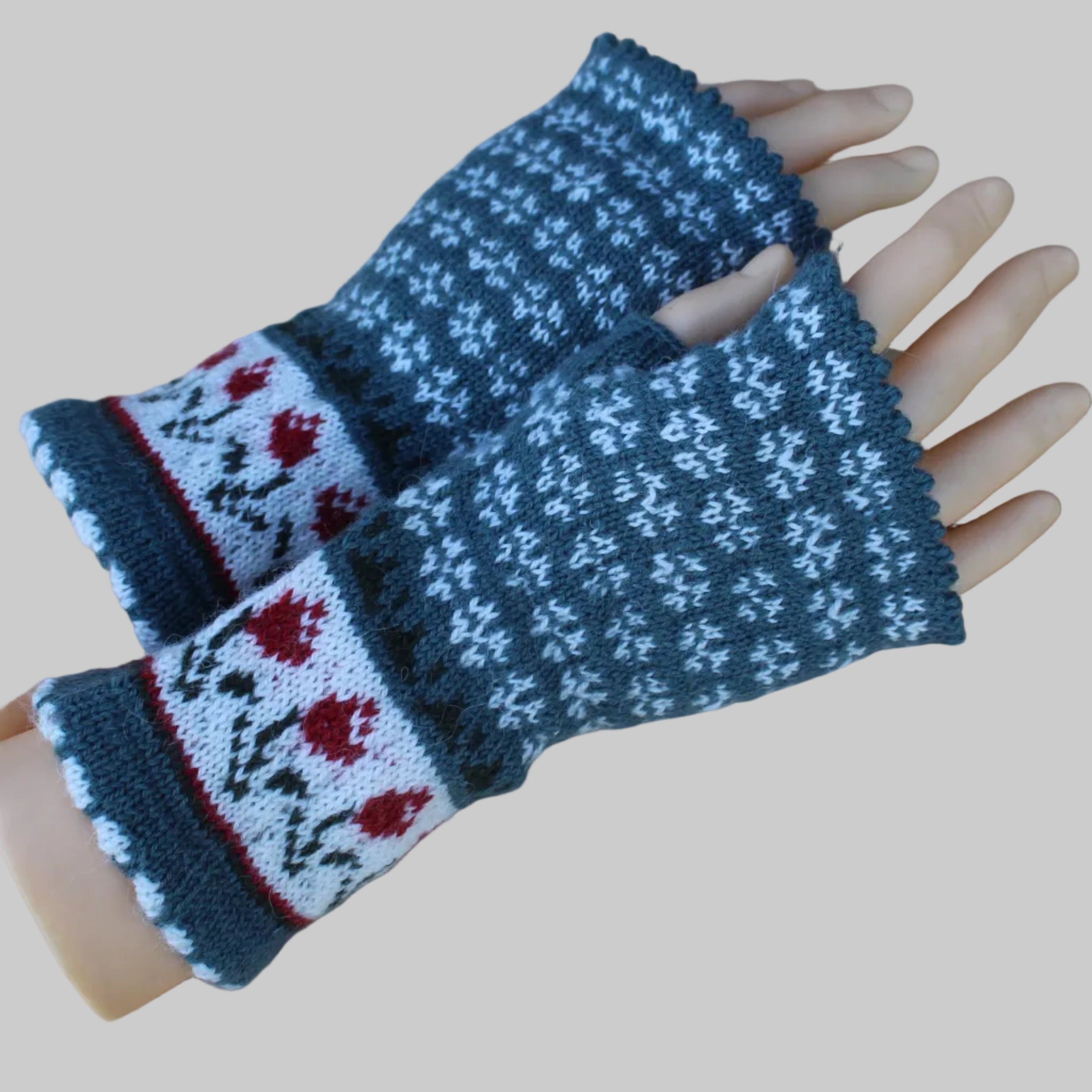 Pair of knitted fingerless gloves with floral pattern on a wooden surface
