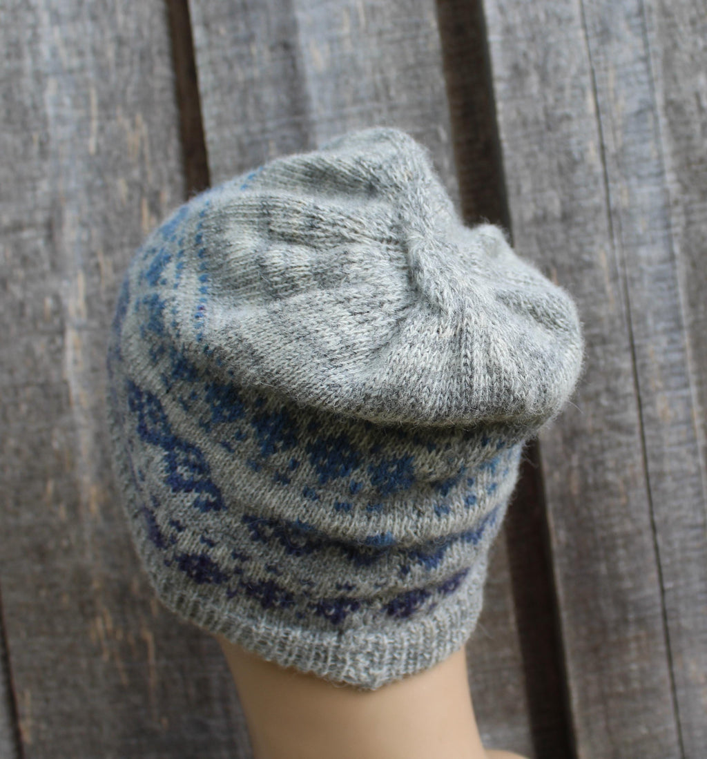 Gray knitted beanie with blue pattern on a wooden surface