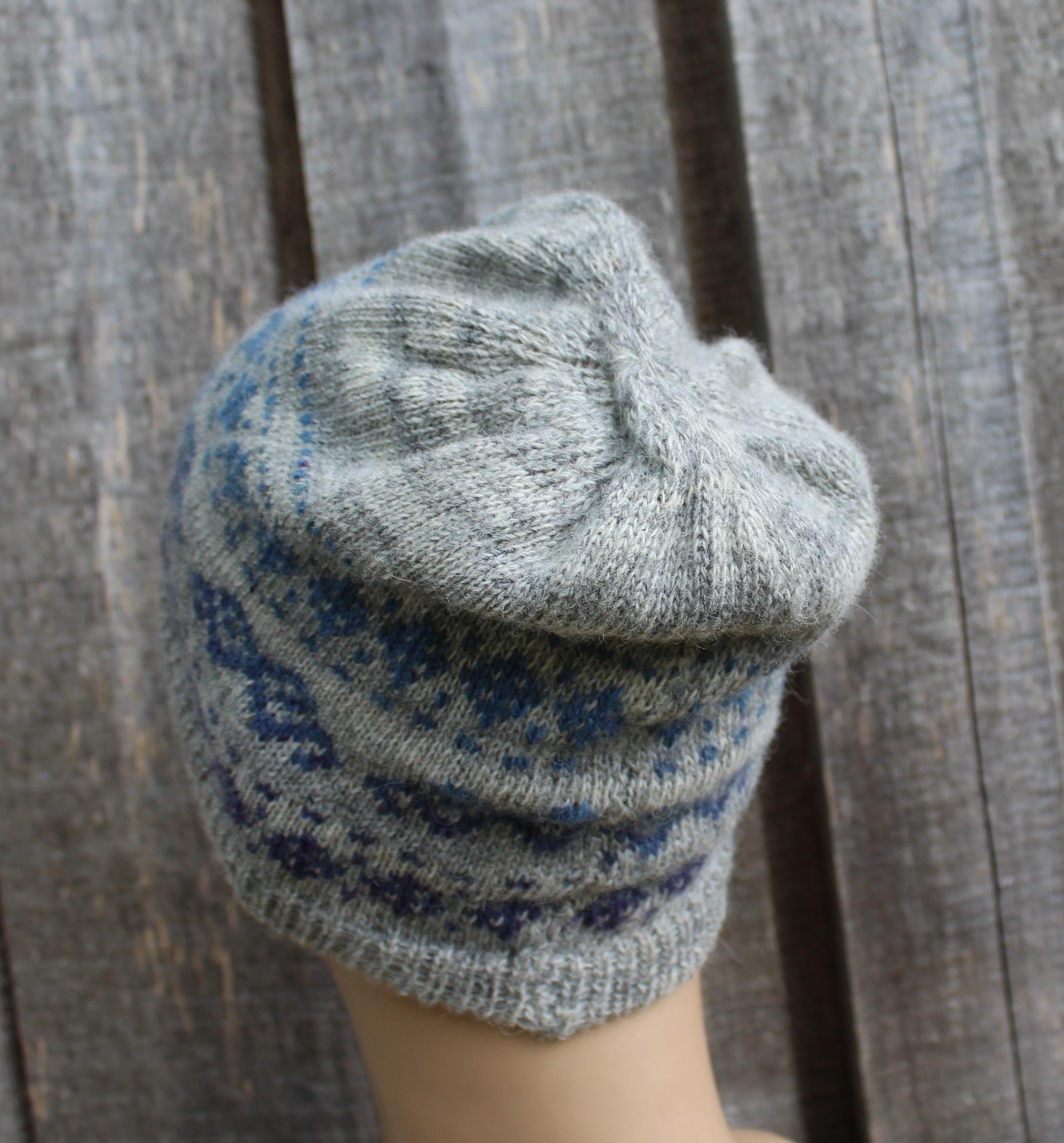 Gray knitted beanie with blue pattern on a wooden surface