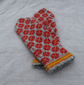 Pair of red and gray patterned mittens on a textured fabric background