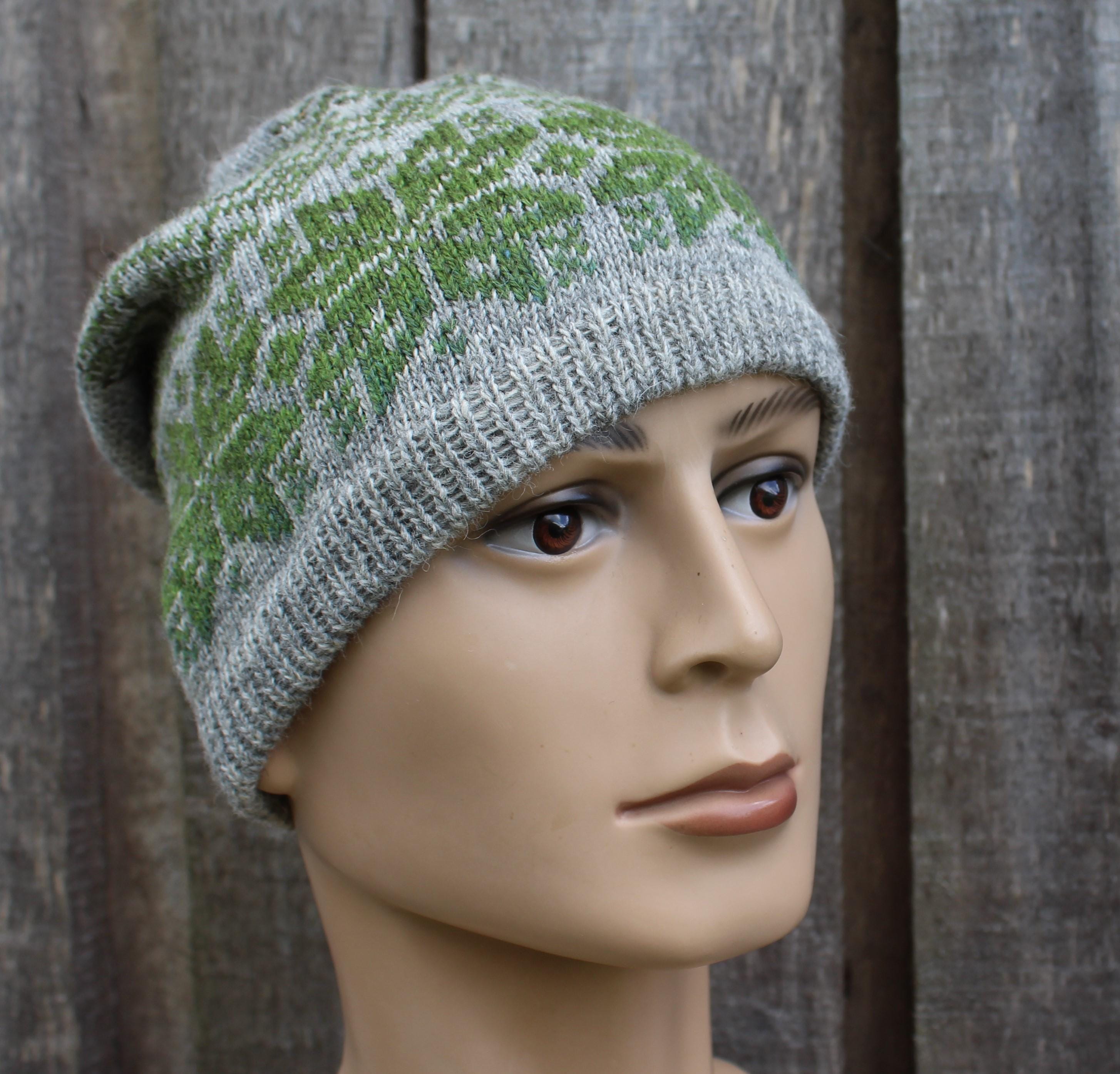 Knitted hat with green and gray pattern on a mannequin head against a wooden background