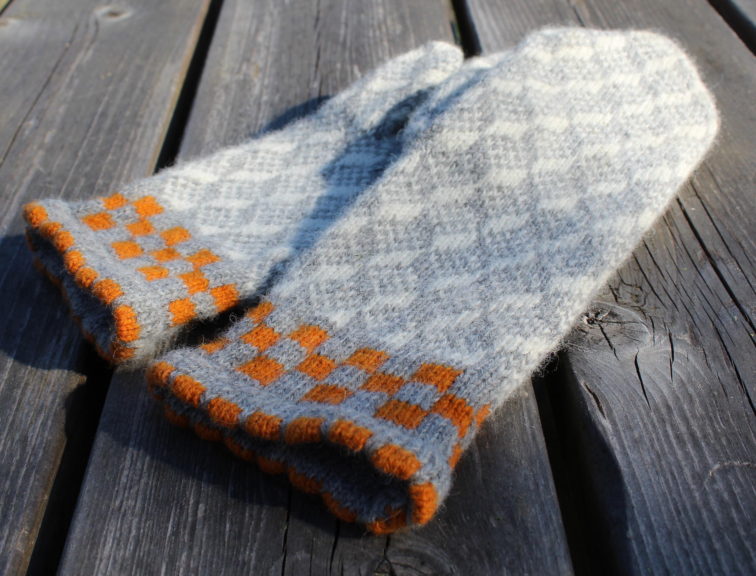 Gray and orange knitted mitten on a wooden surface