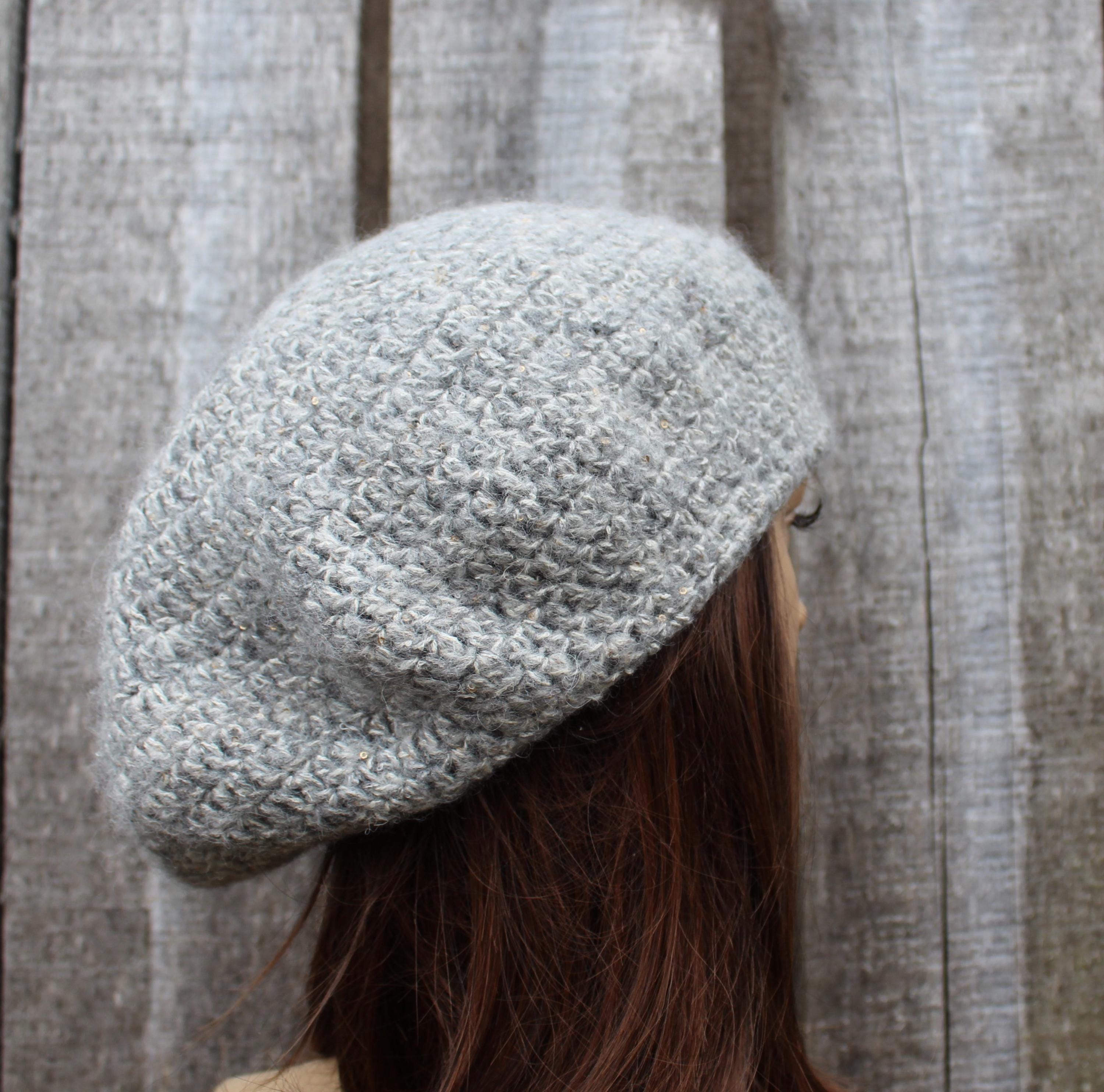 Person wearing a textured gray beret against a wooden background