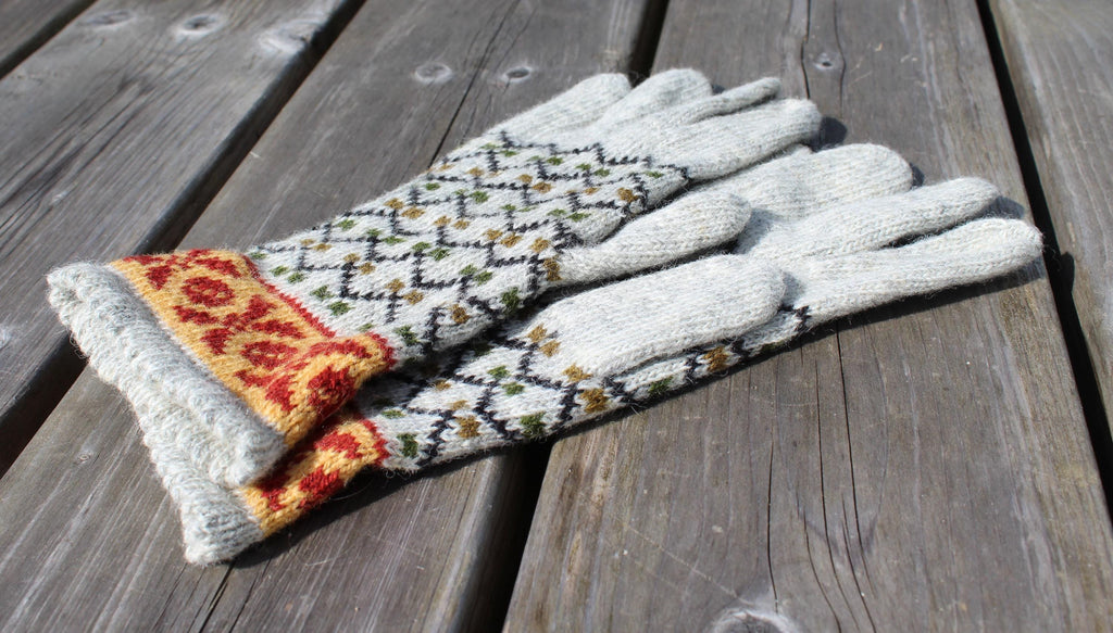 Pair of gloves with patterned cuffs on a wooden surface
