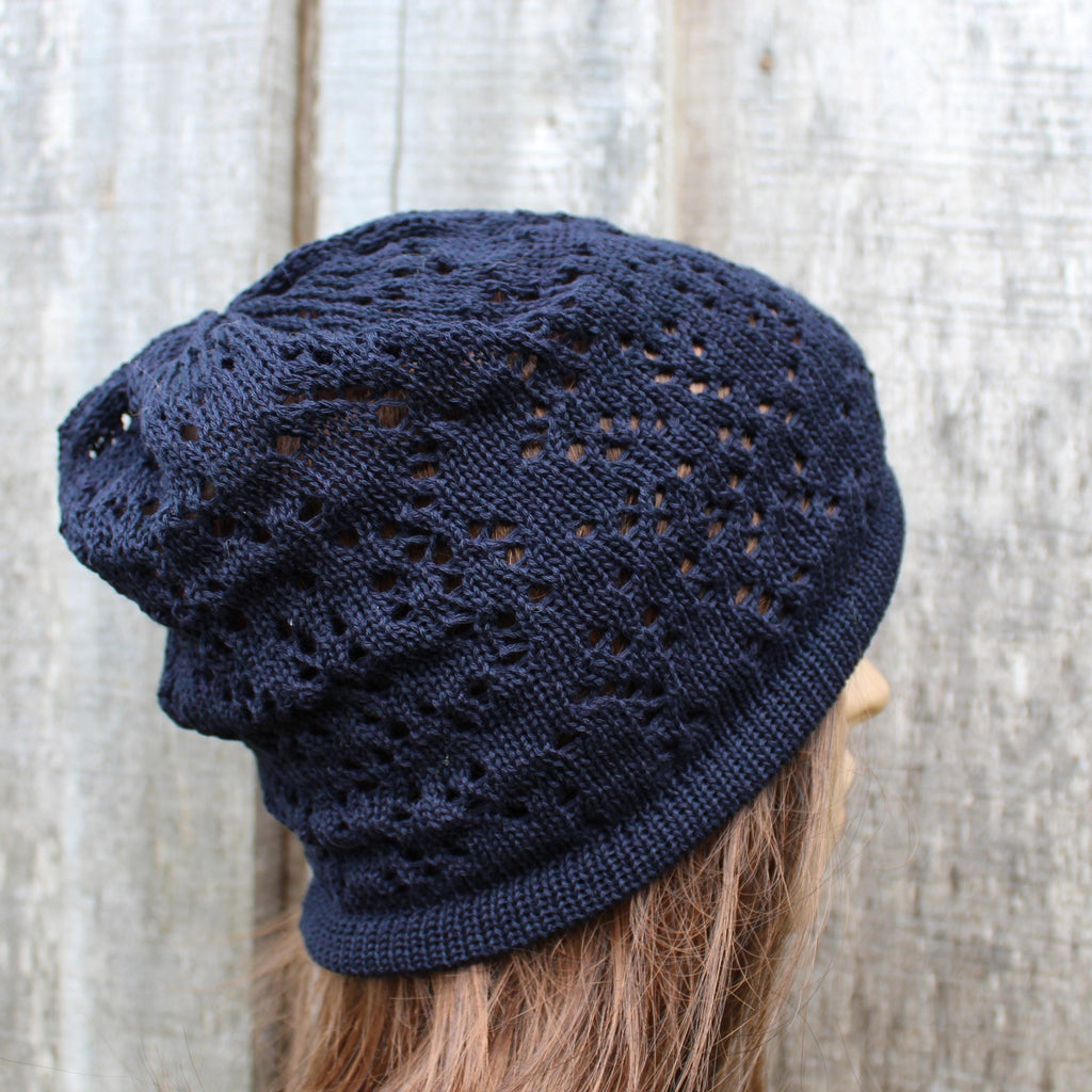 Navy blue knitted beanie on a mannequin head against a textured white background