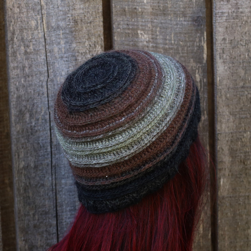 Multicolored knitted beanie with red fringe against a wooden background