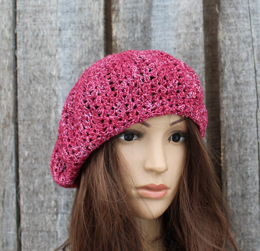 Mannequin head wearing a pink knitted beret against a wooden background