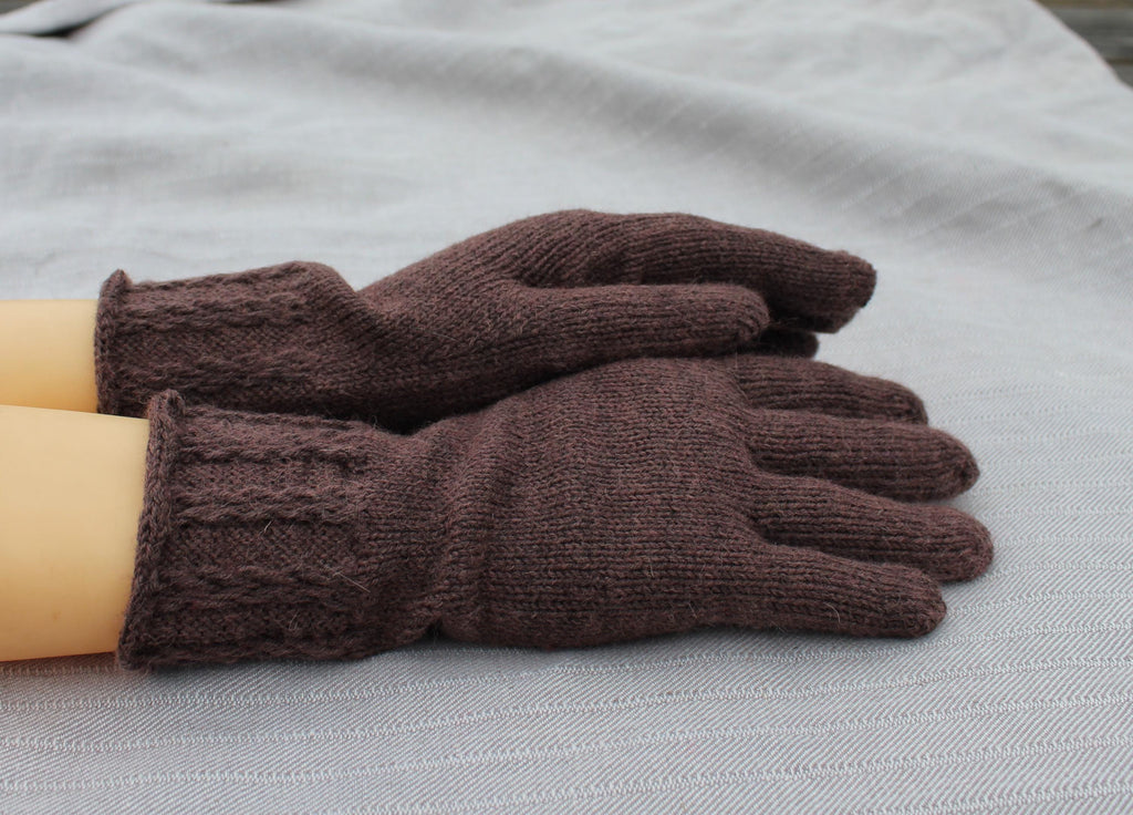 Pair of brown knitted gloves on a gray surface