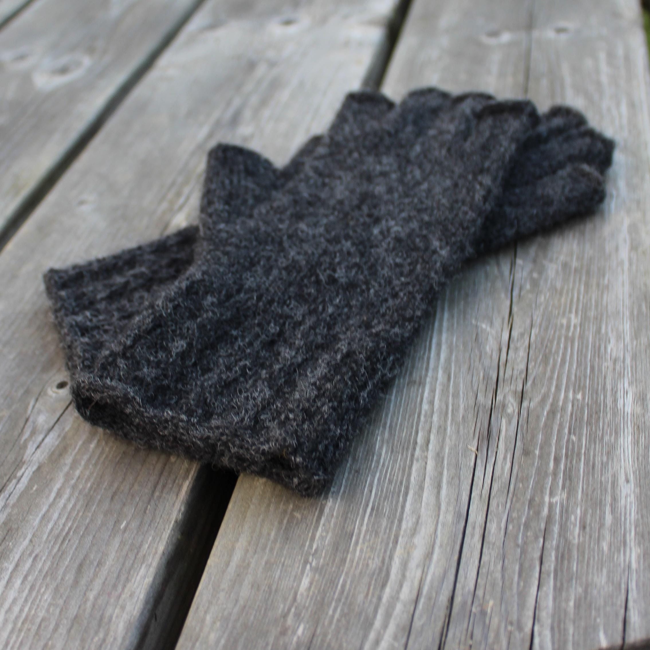 Dark gray fingerless gloves on a wooden surface