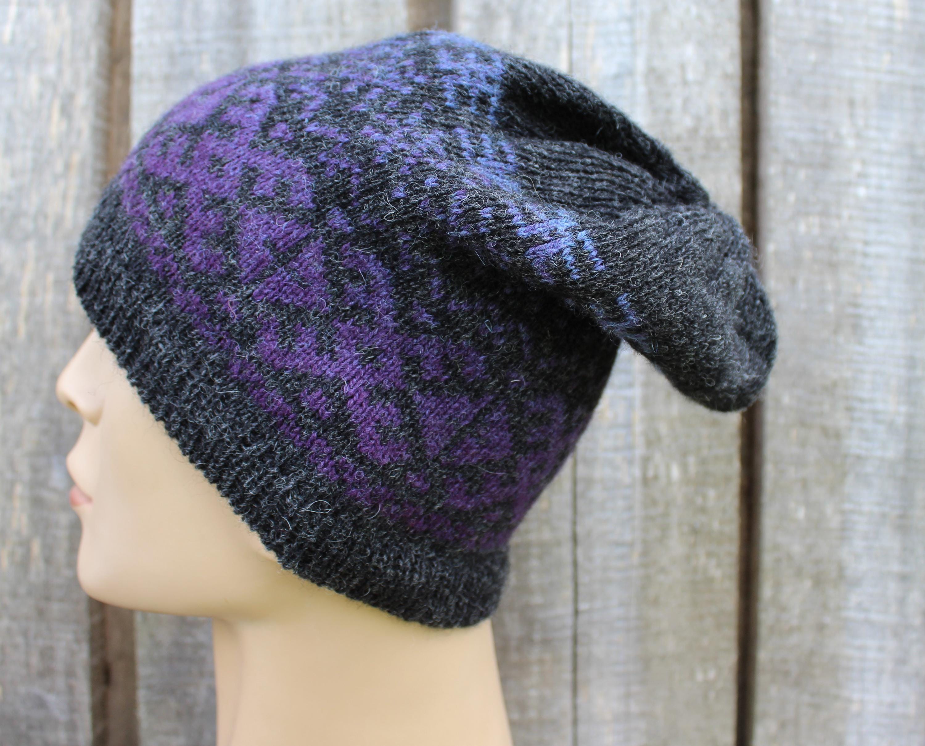 Knitted hat with purple pattern on a mannequin head against a wooden background