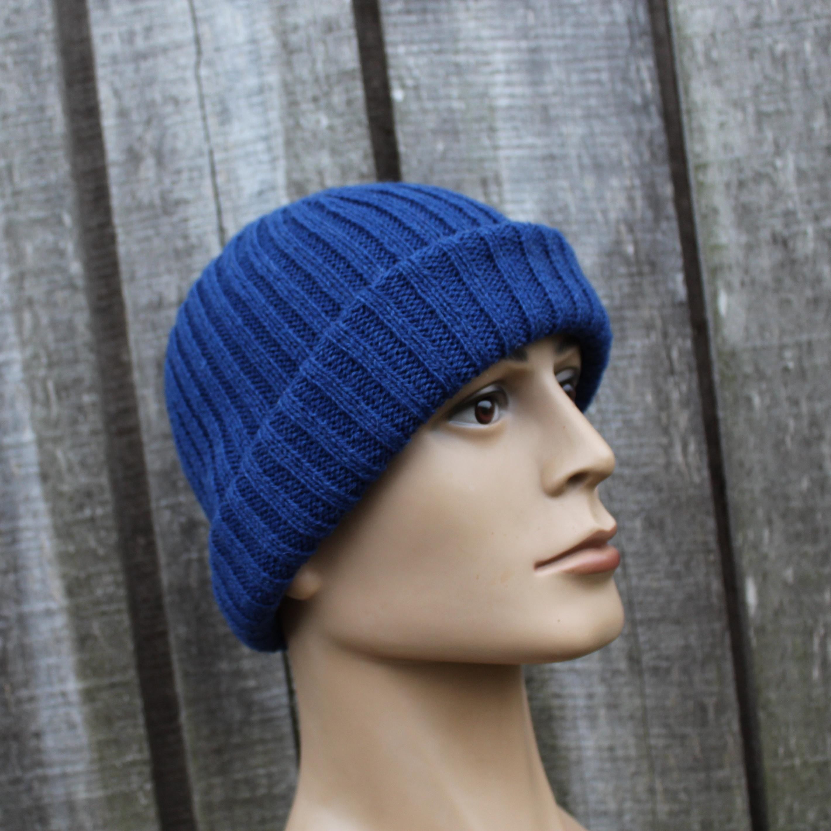 Blue knitted beanie on a mannequin head against a wooden background