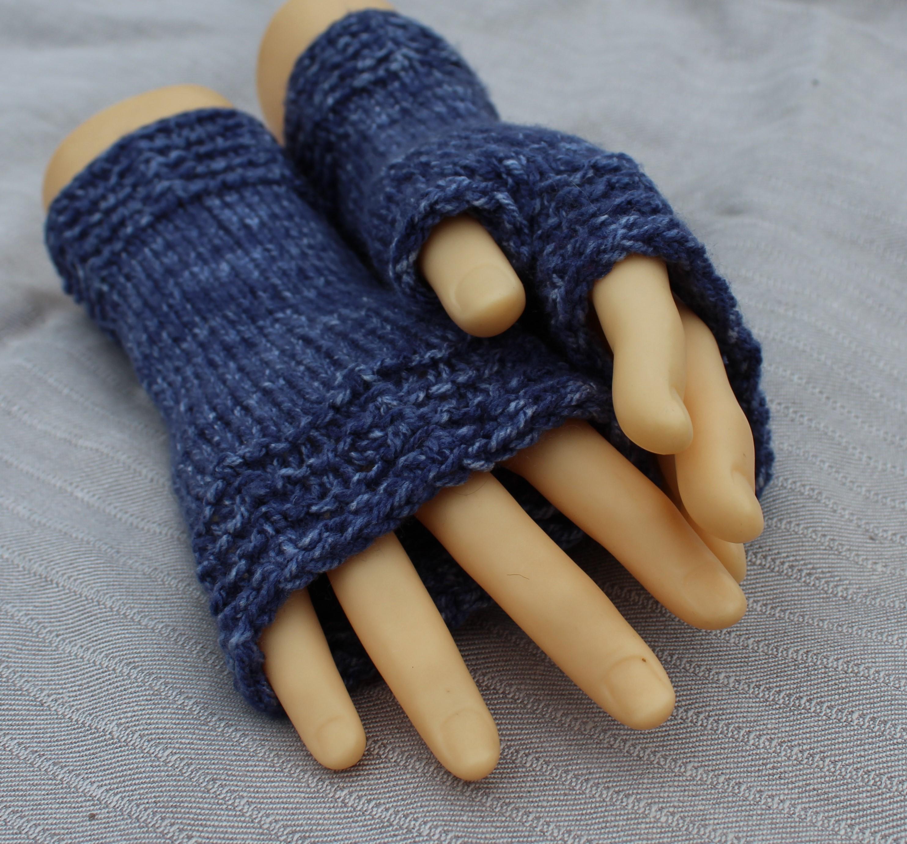 Blue knitted fingerless gloves on a mannequin hand against a gray background
