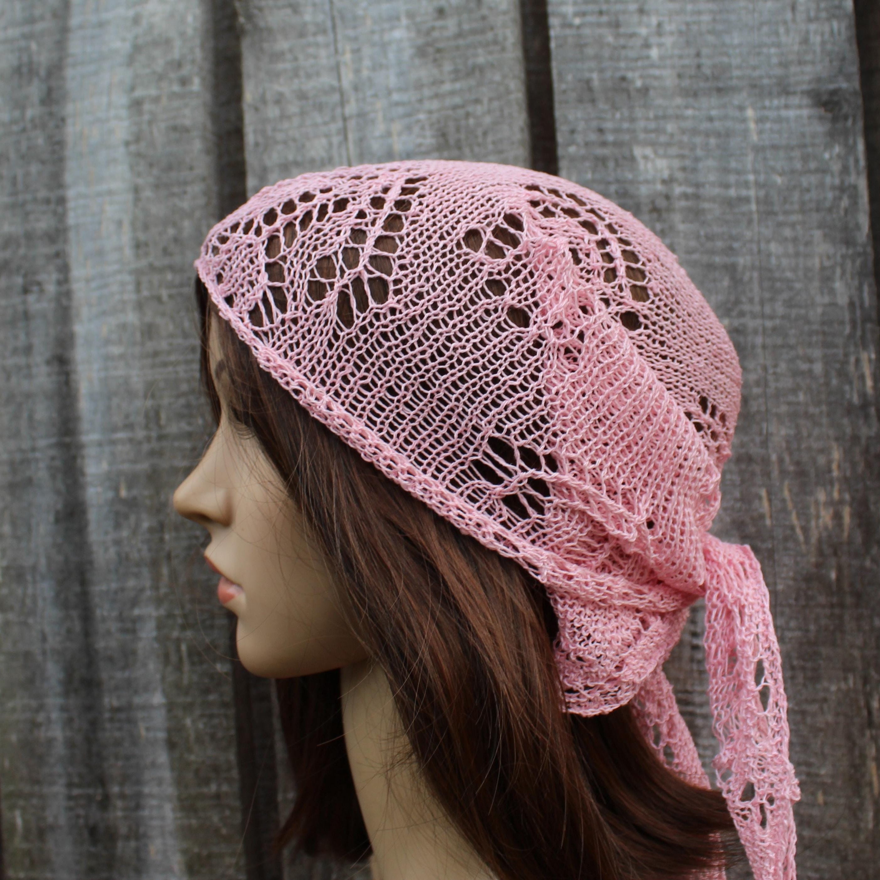 Pink knitted headscarf on a mannequin against a wooden background