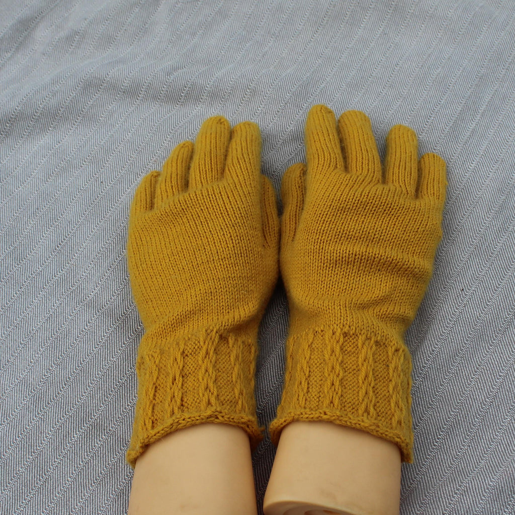 Pair of mustard yellow knitted gloves on a gray fabric background