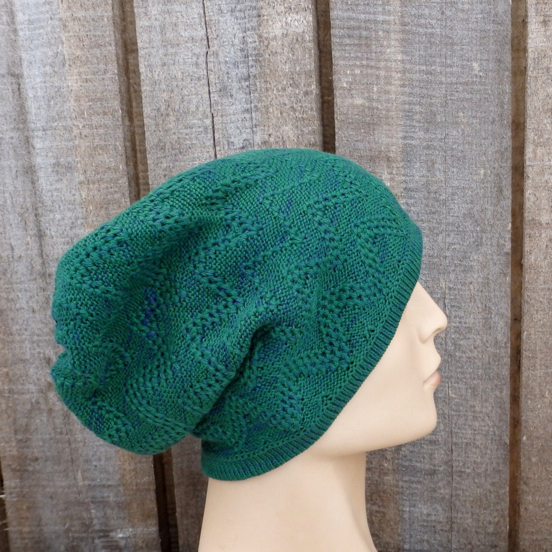 Green knitted hat on a mannequin head against a wooden background