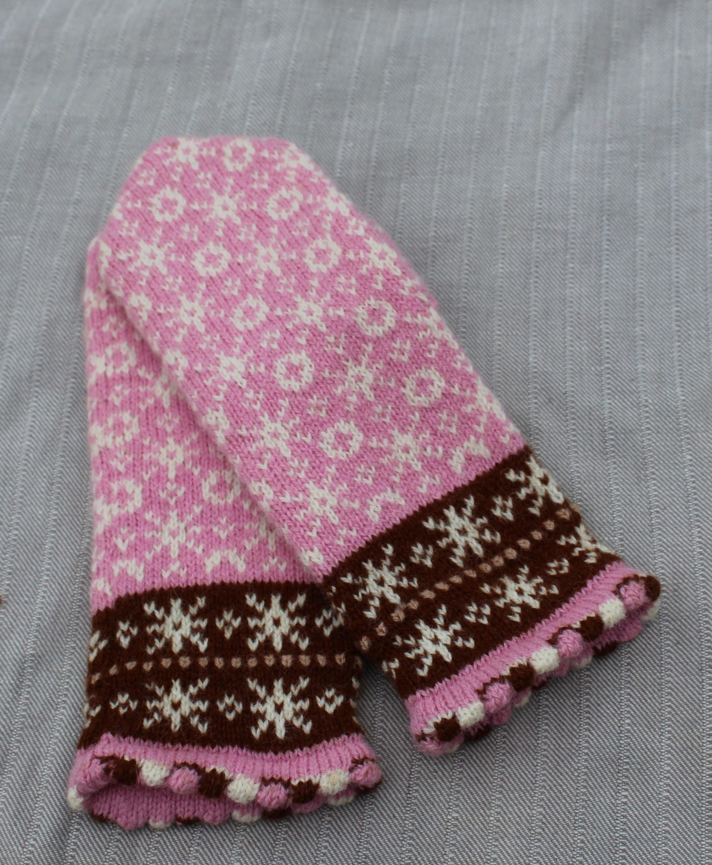 Knitted mittens with pink and brown pattern on a gray background