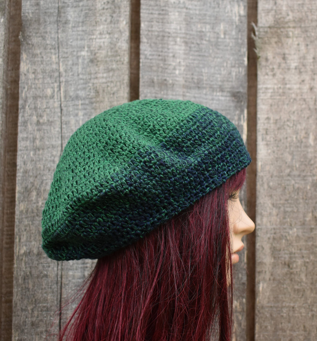 Person wearing a green knitted beret against a wooden fence background