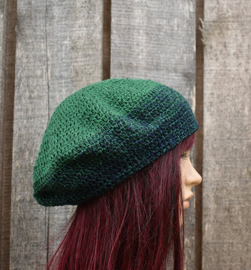 Person wearing a green knitted beret against a wooden fence background