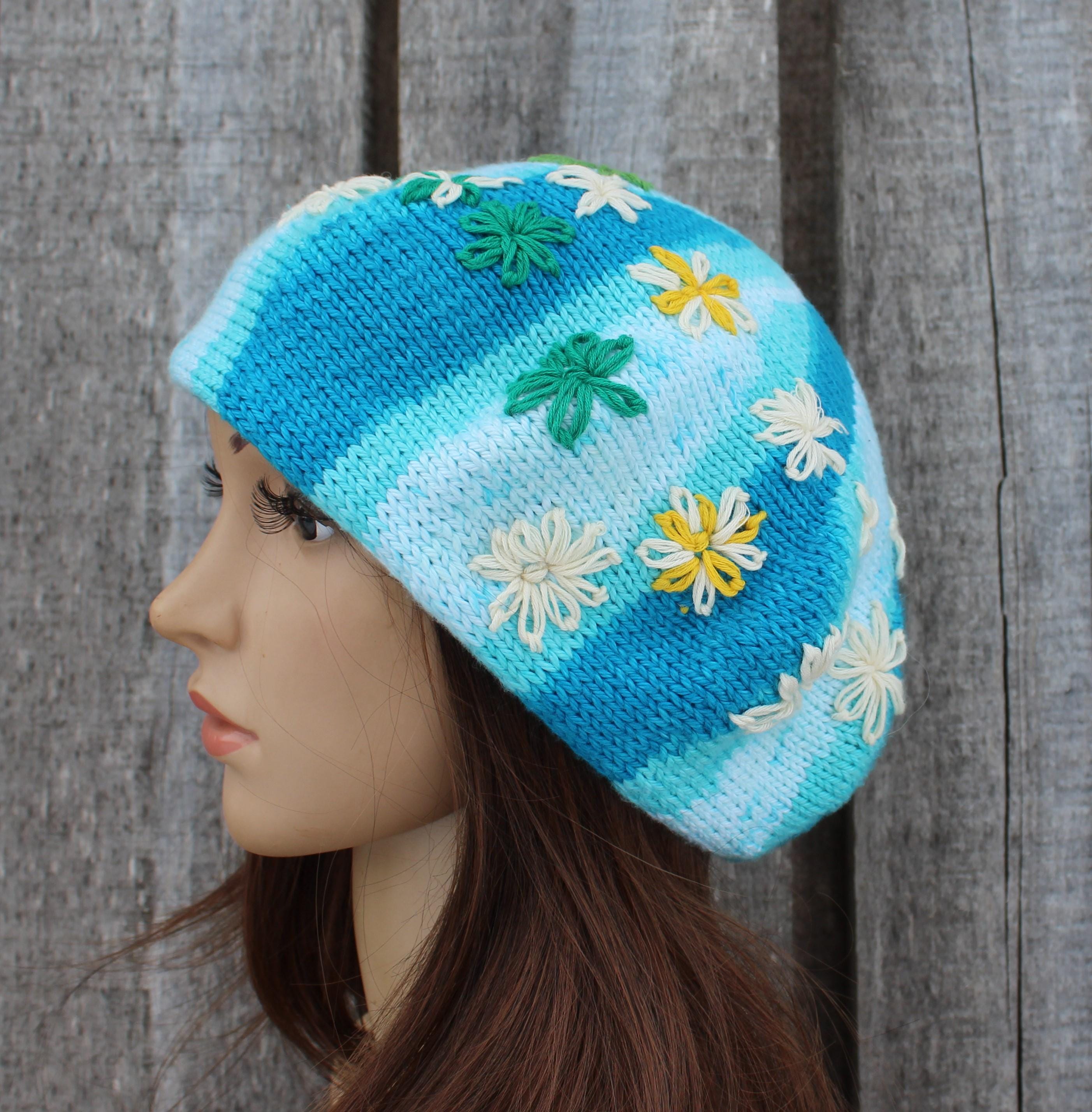 Knitted hat with floral patterns on a mannequin head against a wooden background