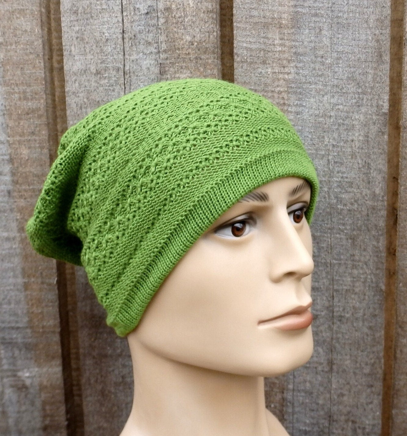 Green knitted beanie on a mannequin head against a wooden background