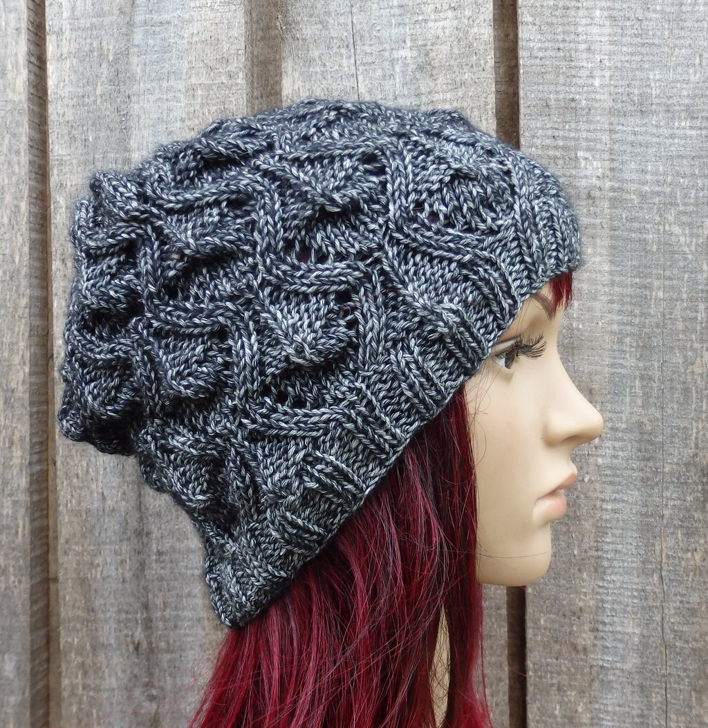 Knitted gray beanie on a mannequin head against a wooden background