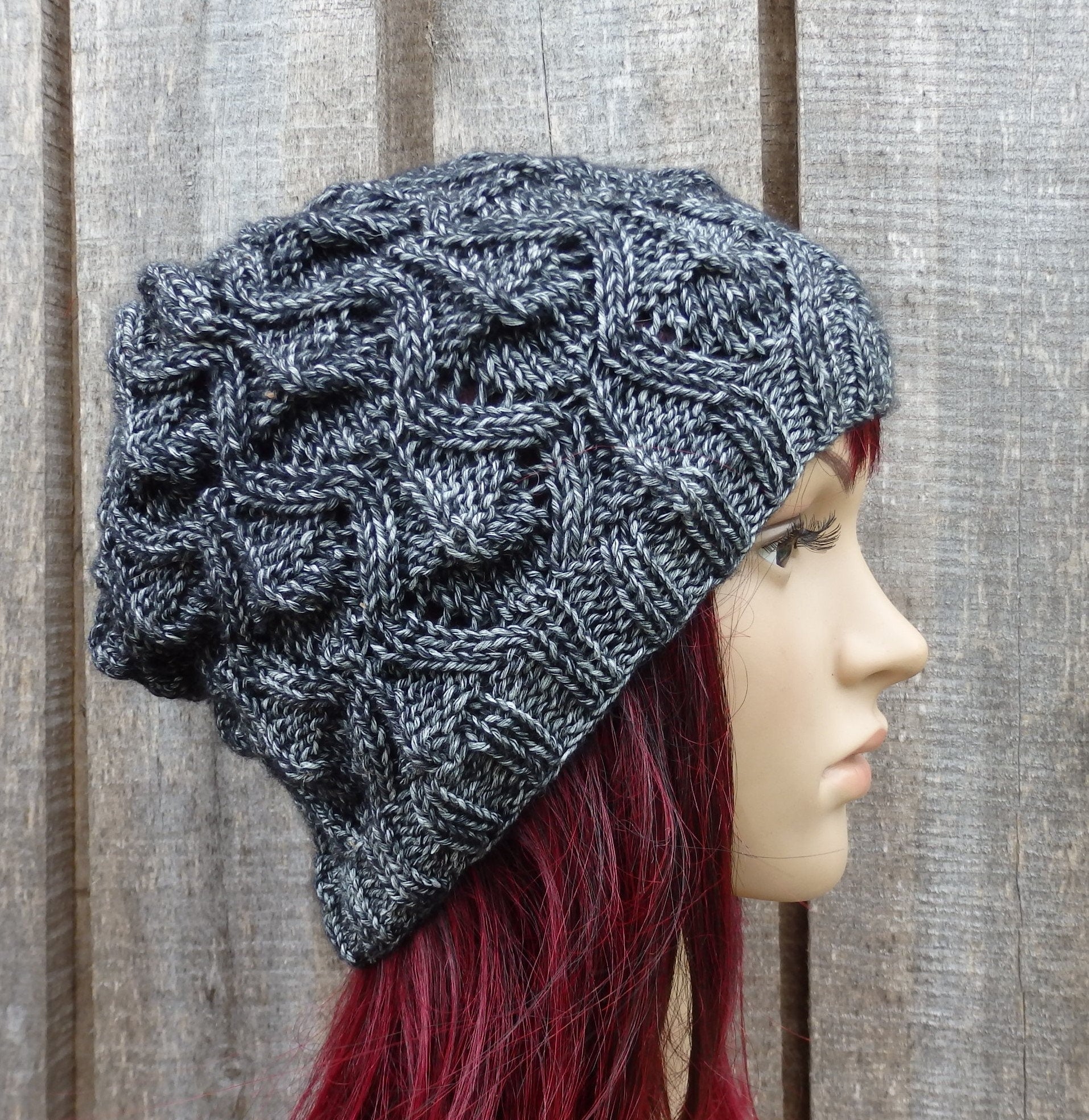 Knitted gray beanie on a mannequin head against a wooden background