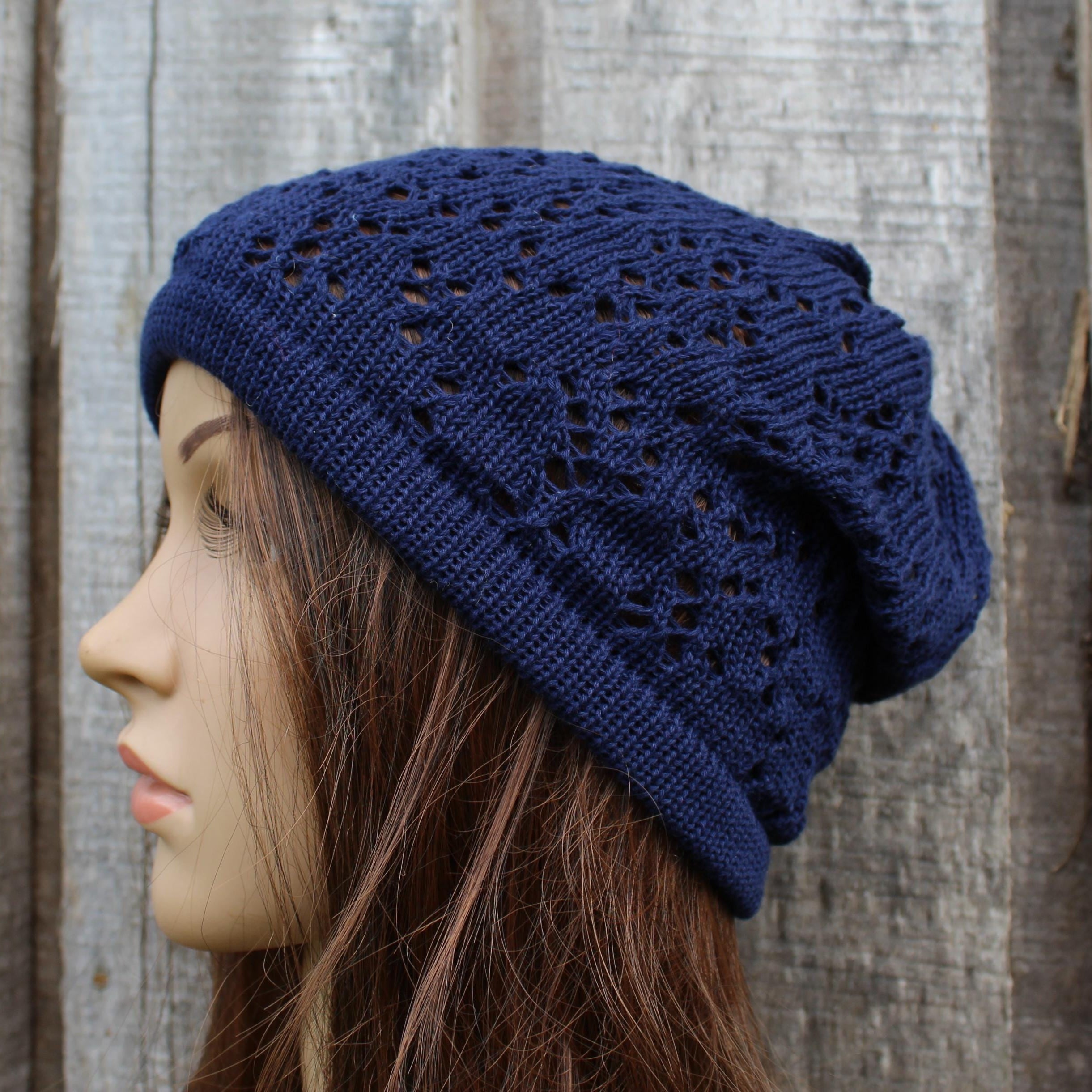 Navy blue knitted beanie worn by a mannequin against a wooden background