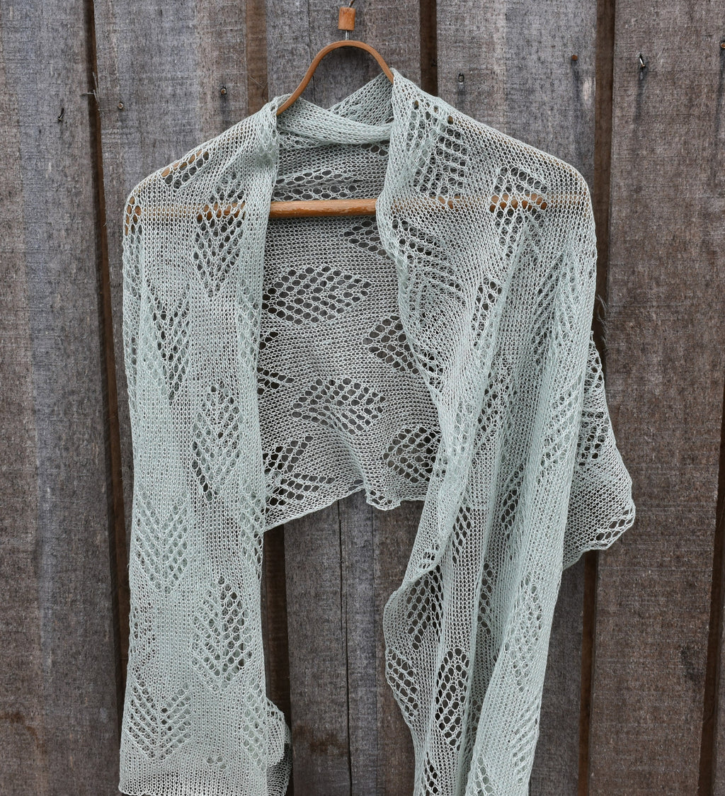 Knitted shawl on a wooden hanger against a wooden background