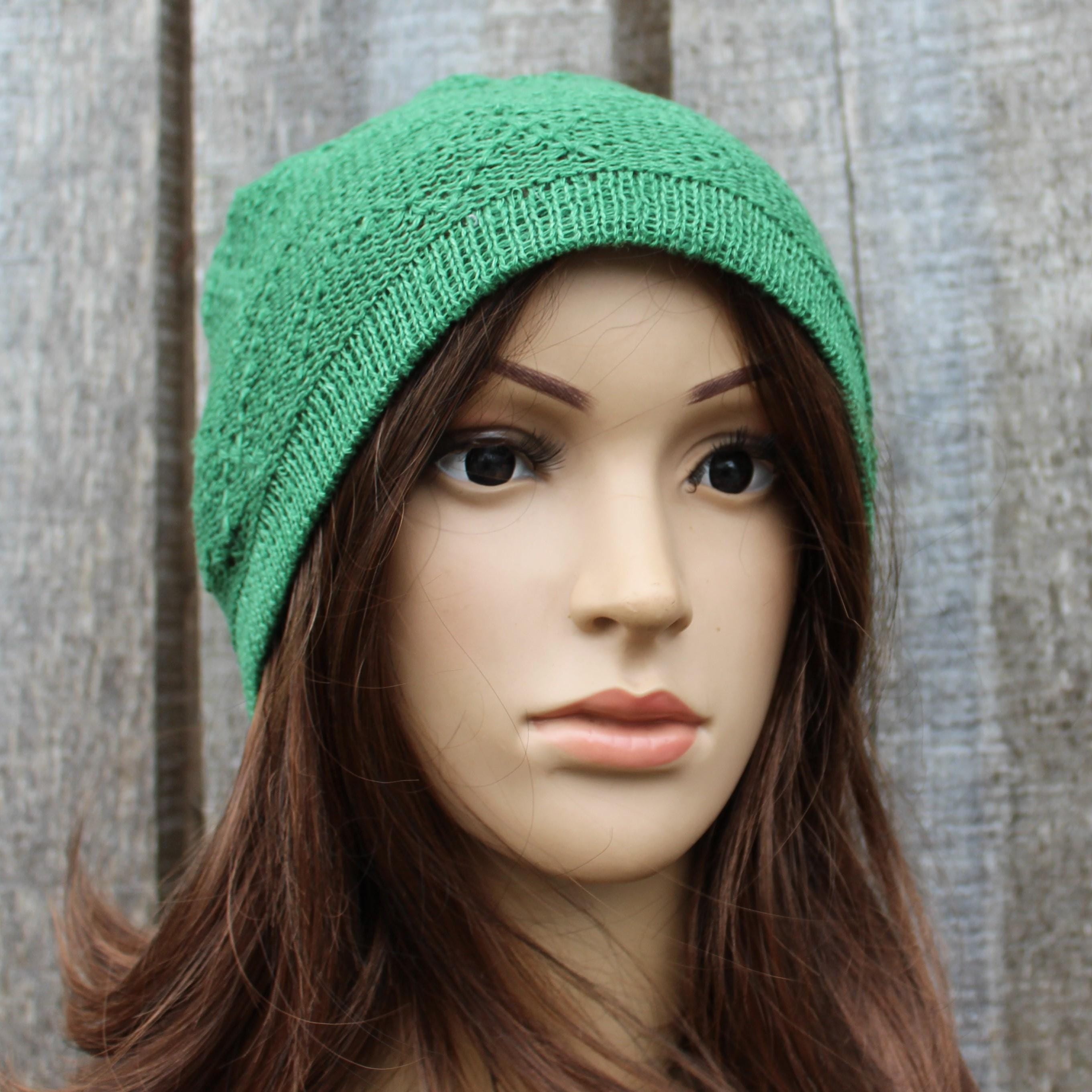 Mannequin head wearing a green knitted beanie against a wooden background