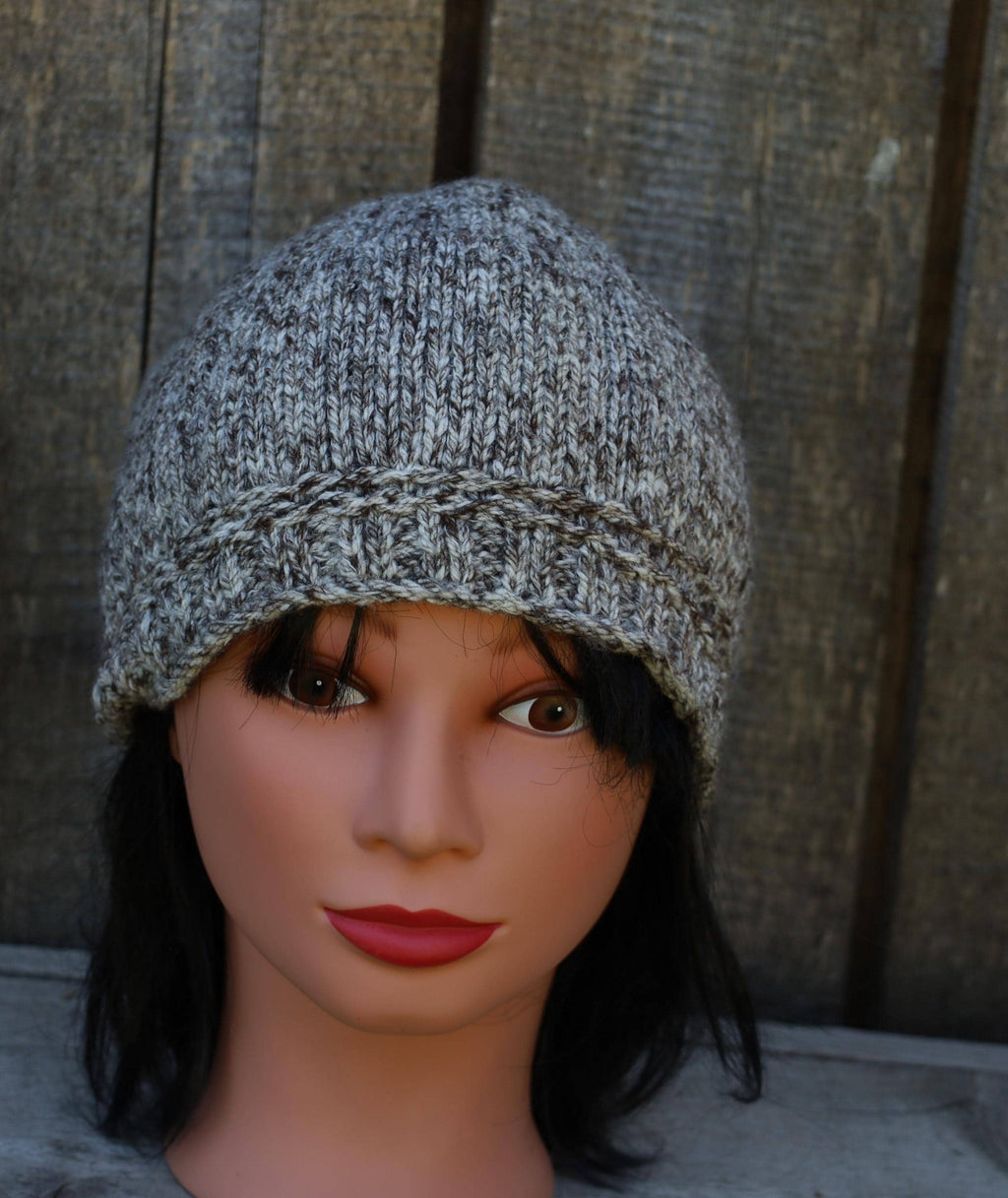 Knitted gray beanie on a mannequin head against a wooden background