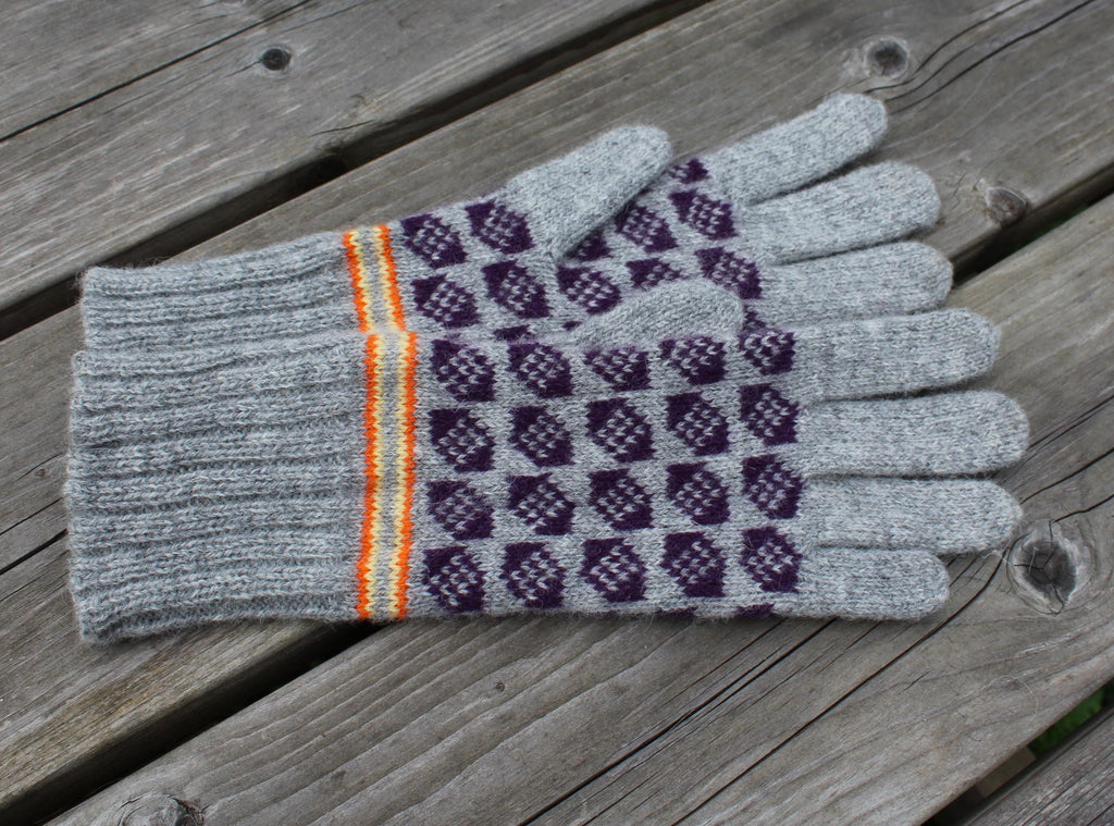 Pair of gloves with gray cuffs and purple patterned palm on a wooden surface