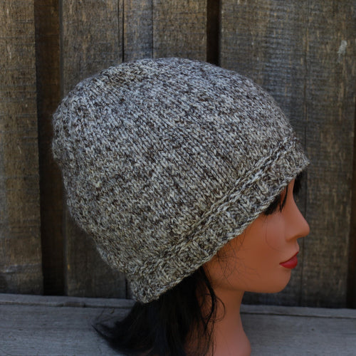 Knitted beanie on a mannequin head against a wooden background