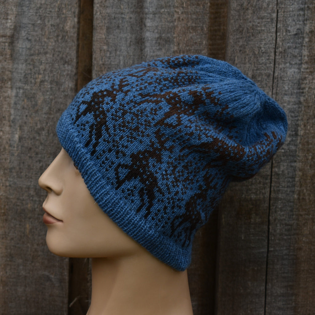 Blue knitted hat with black patterns on a mannequin head against a wooden background