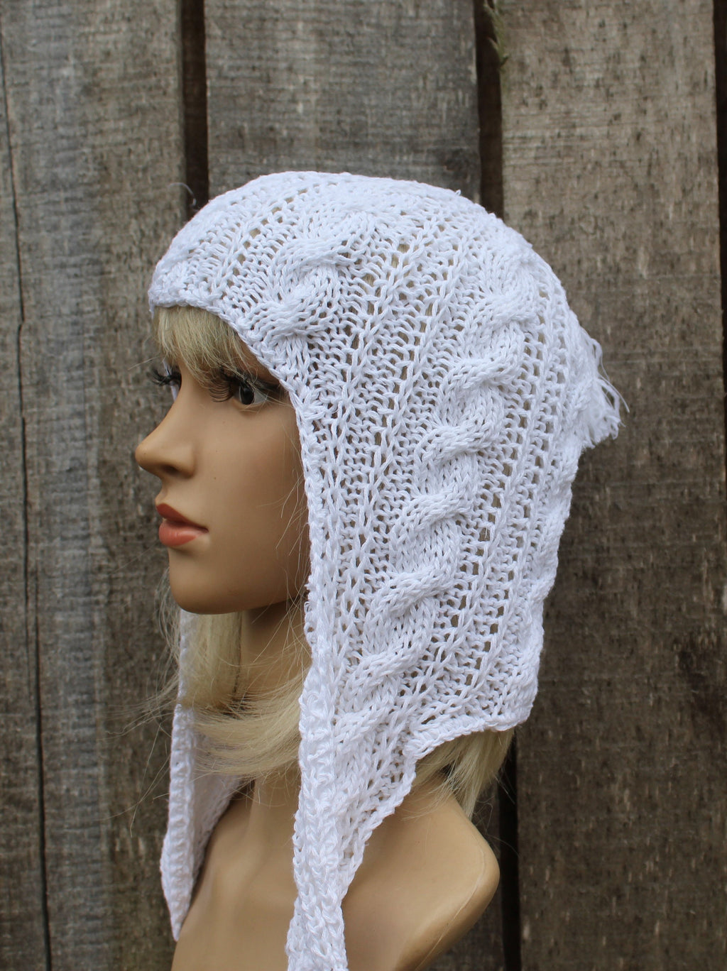 White knitted hood on a mannequin against a wooden background